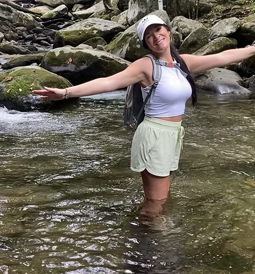 Reviewer standing in water on hike wearing the white top with shorts