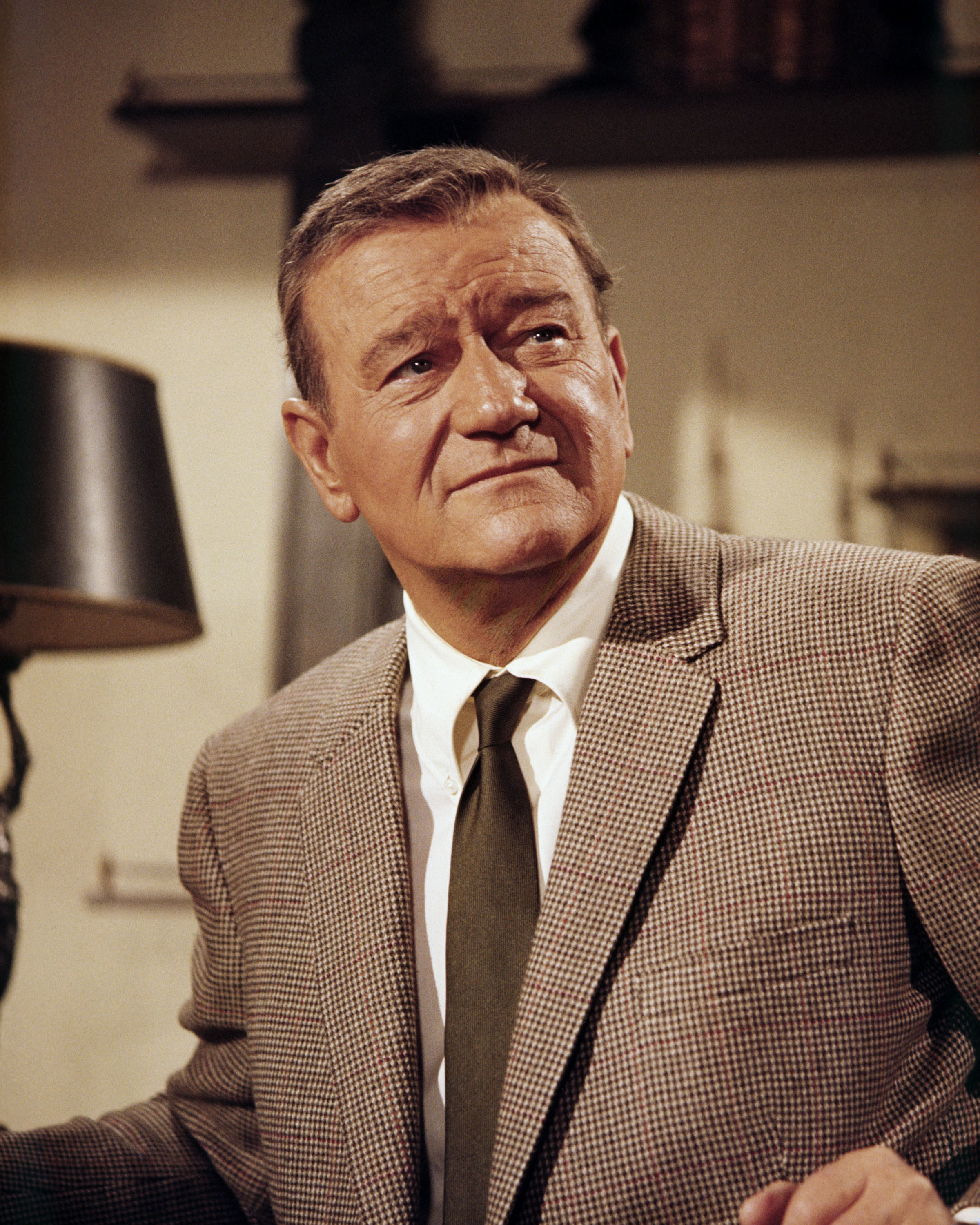 A portrait of John Wayne wearing a suit and tie