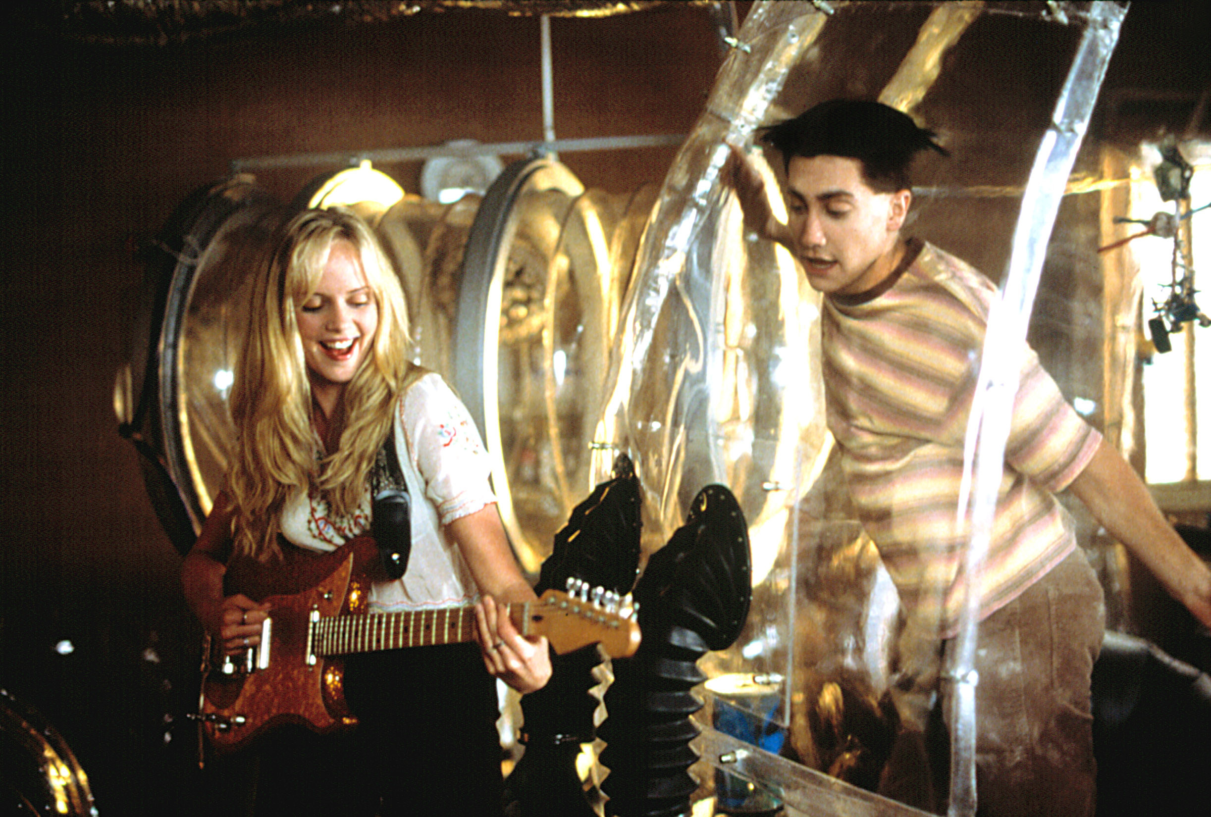 boy in a bubble watches as a girl plays guitar