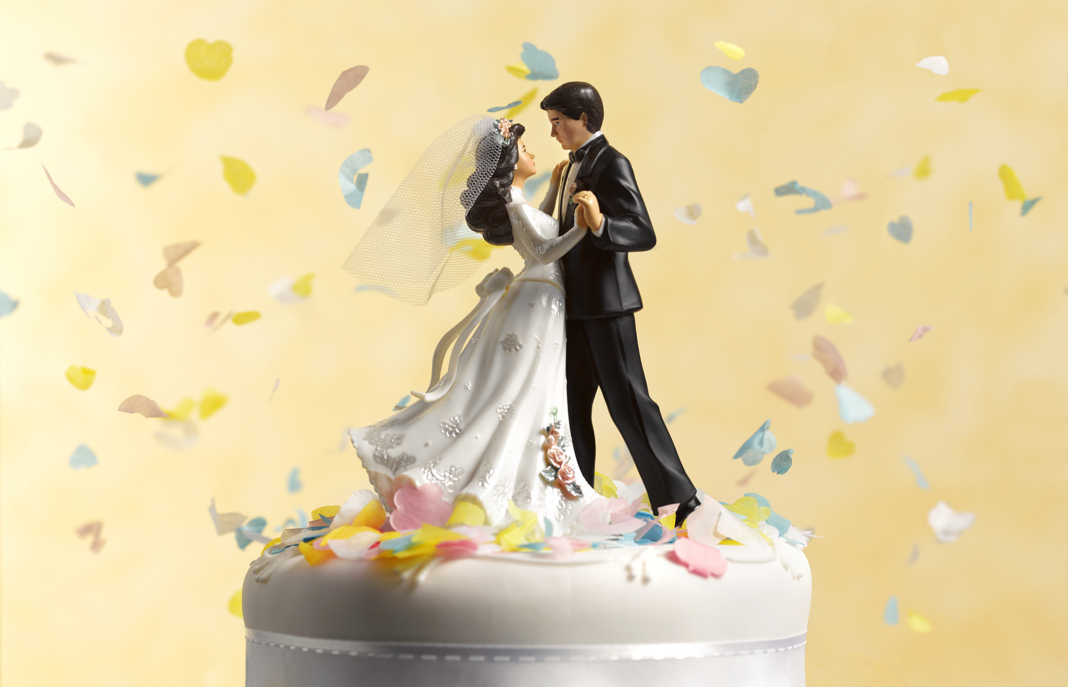 A wedding cake topper against a yellow background