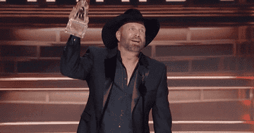 Garth Brooks holding up an award onstage at the CMAs