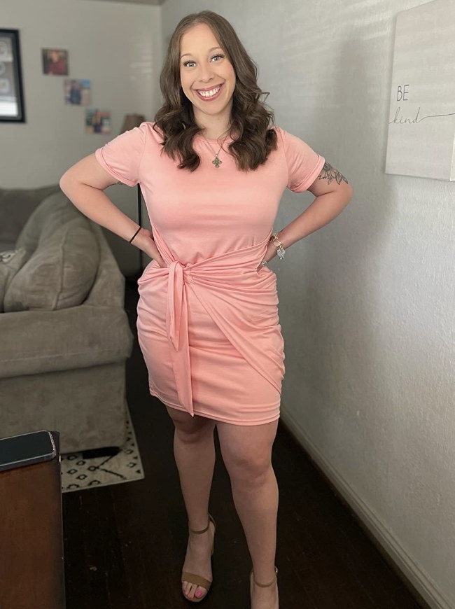 A reviewer wearing a pink bodycon wrap dress