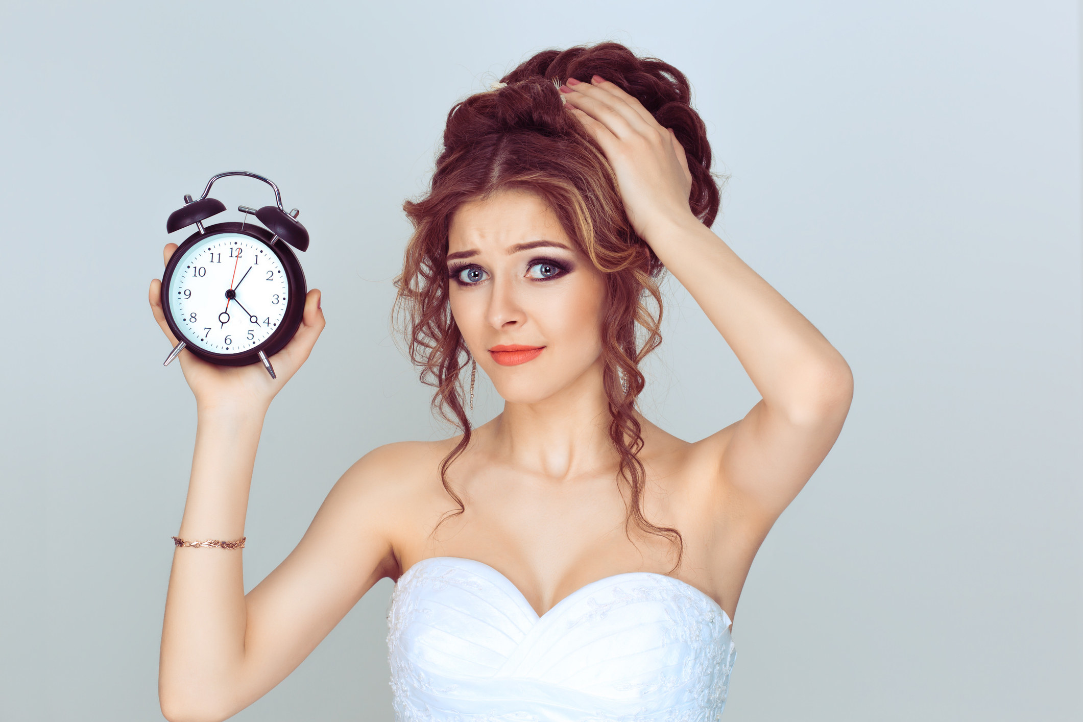 a late bride holds up an alarm clock