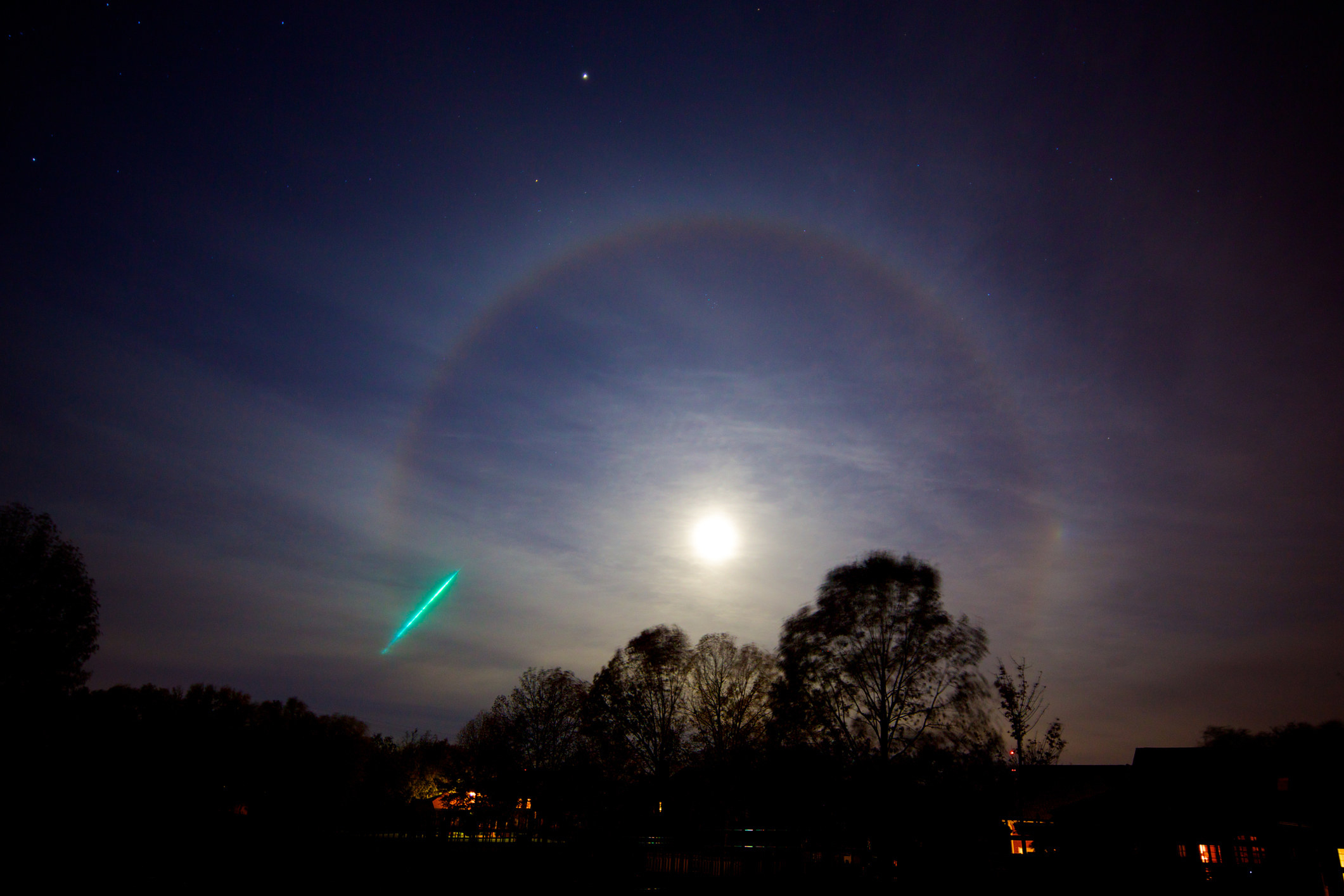 A circle of light around the moon and a meteor.