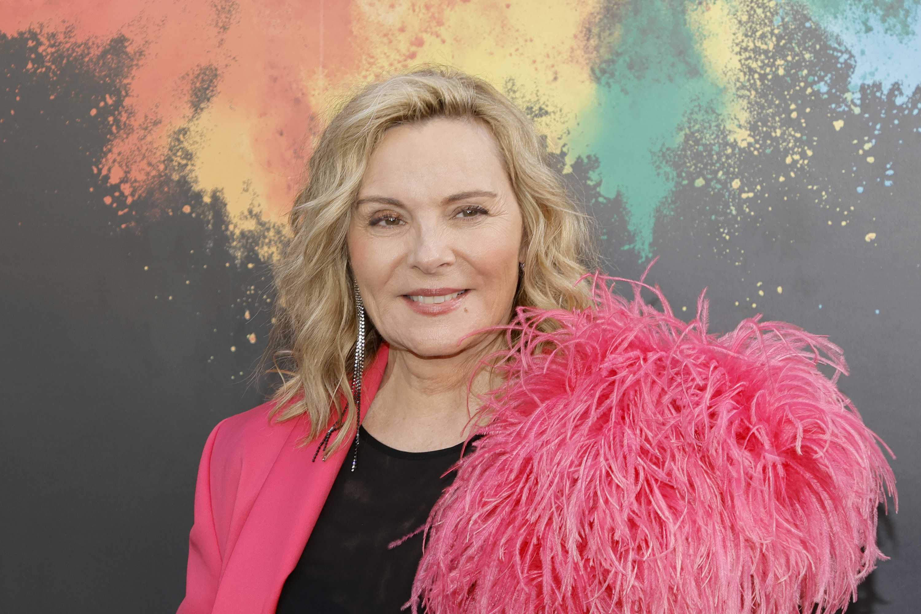 Close-up of Kim smiling and wearing a suit jacket with a feathery accent