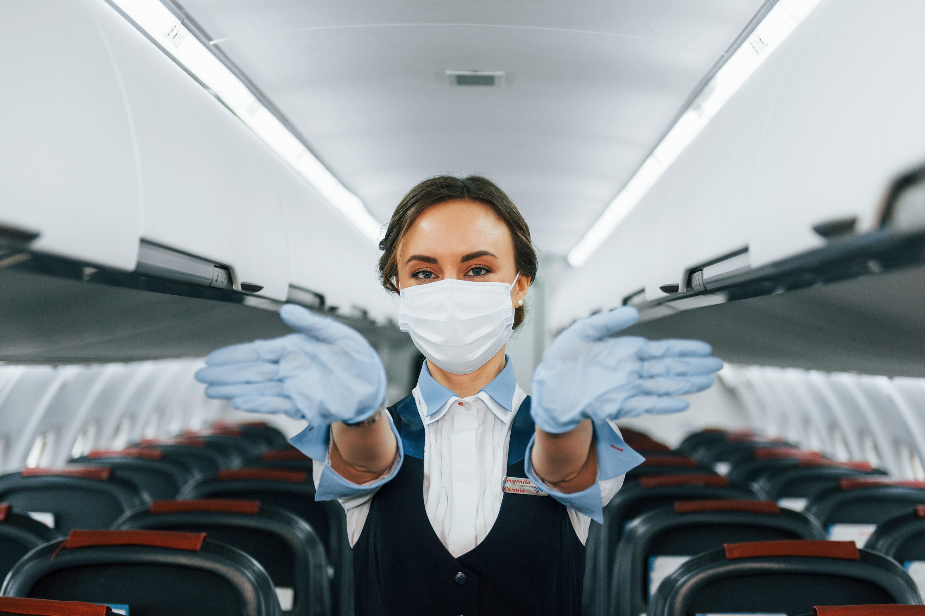 A flight attendant wearing a surgical mask on a plane