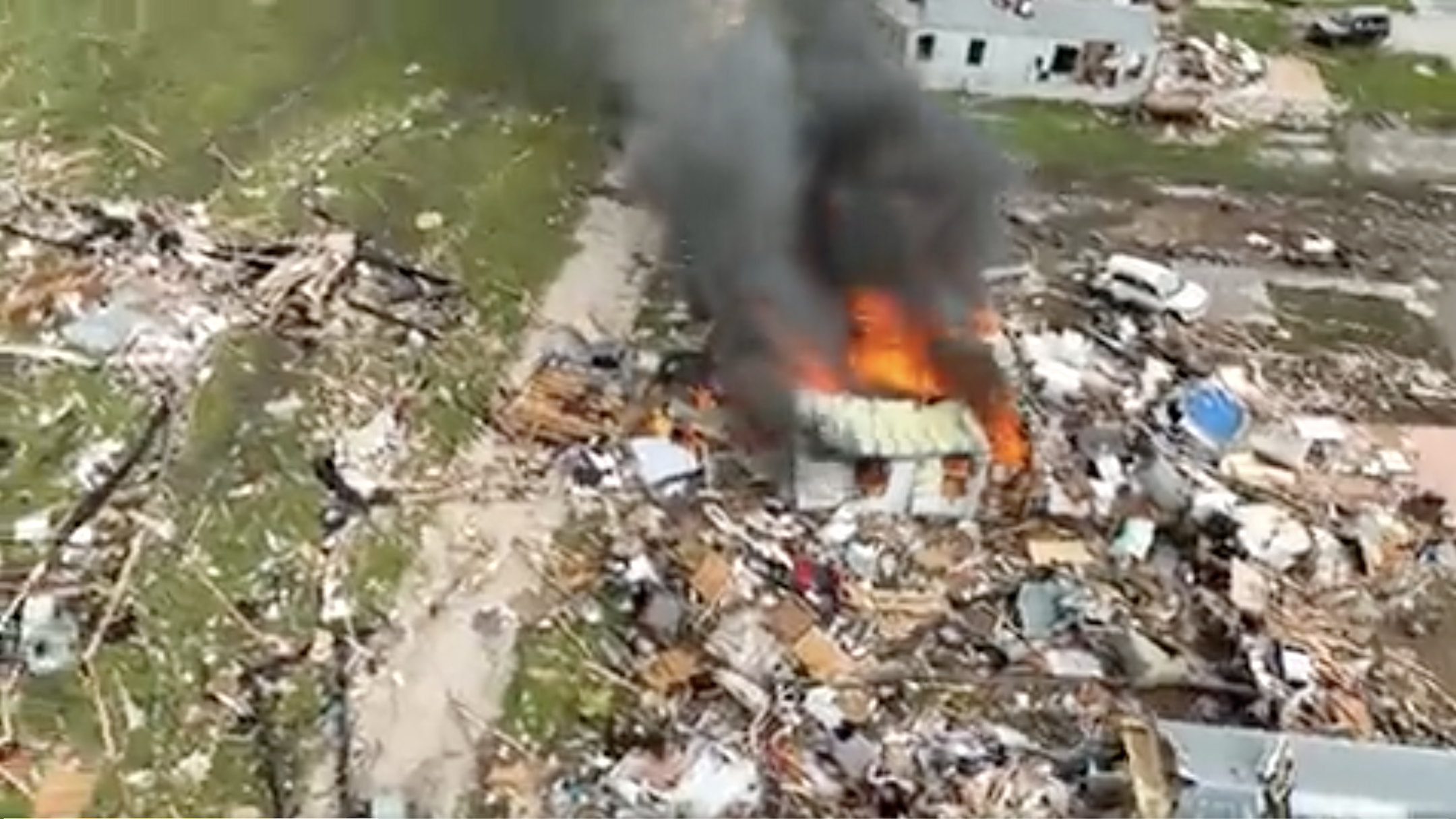 Overhead scene of destruction with one house on fire