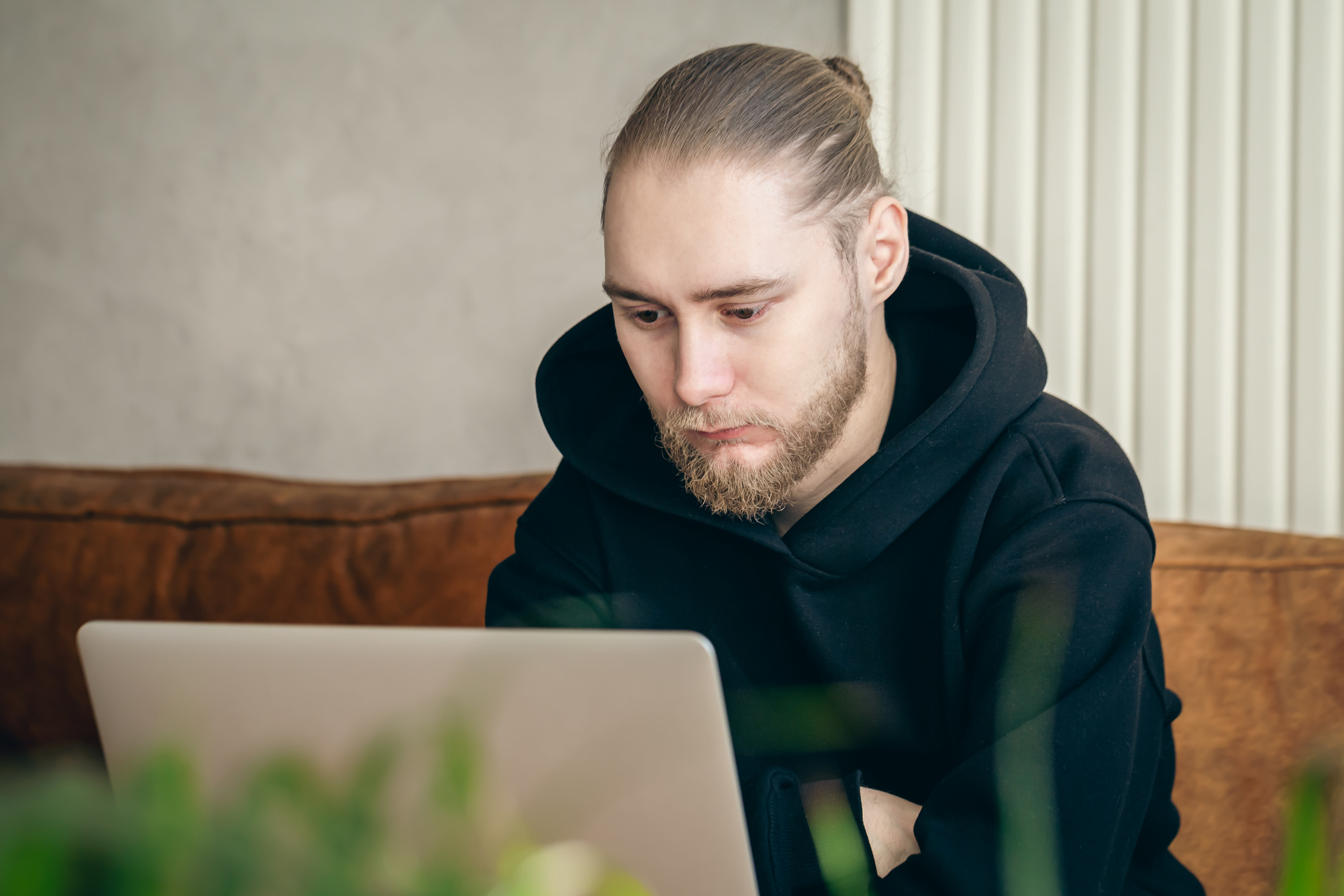 A young person in a hoodie working on a laptop