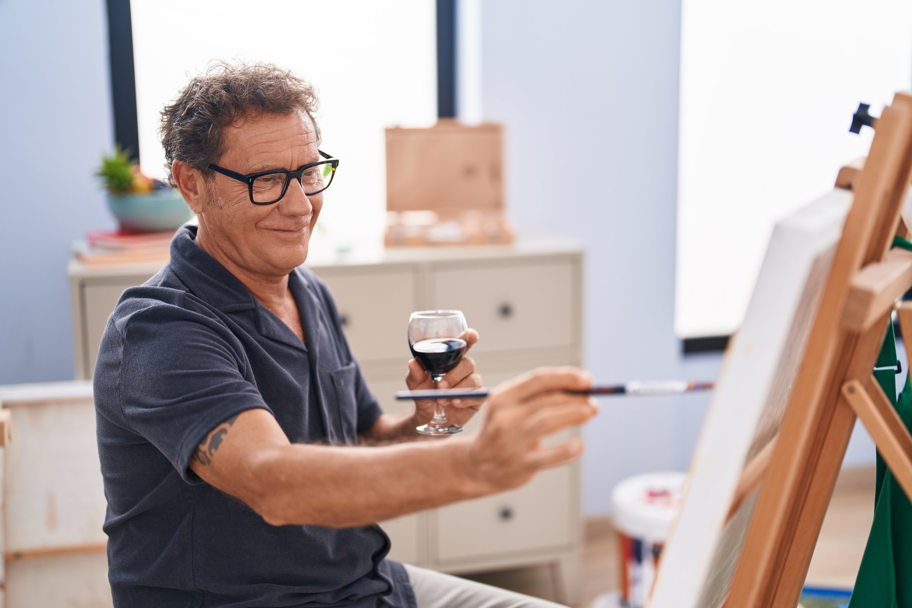A person drinking wine and painting