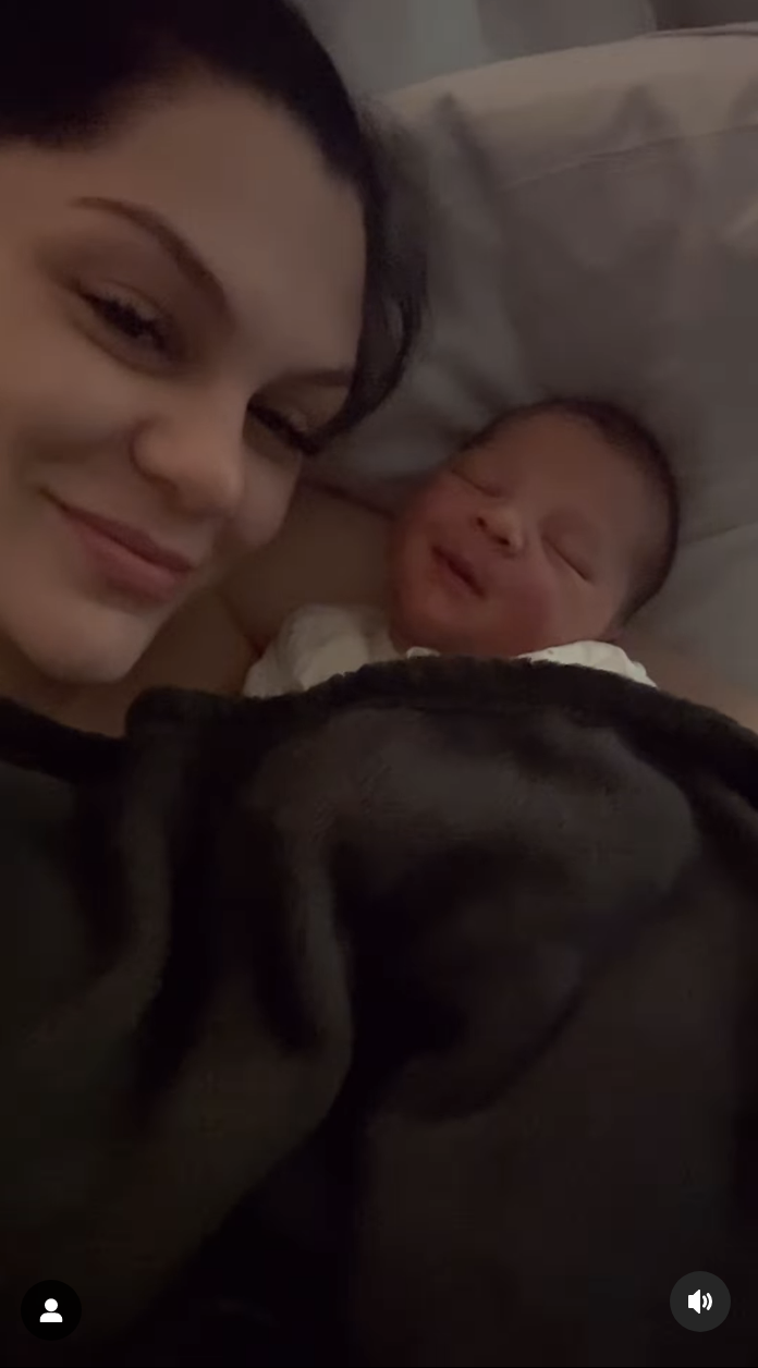 Jessie smiling and lying on a pillow with her baby next to her