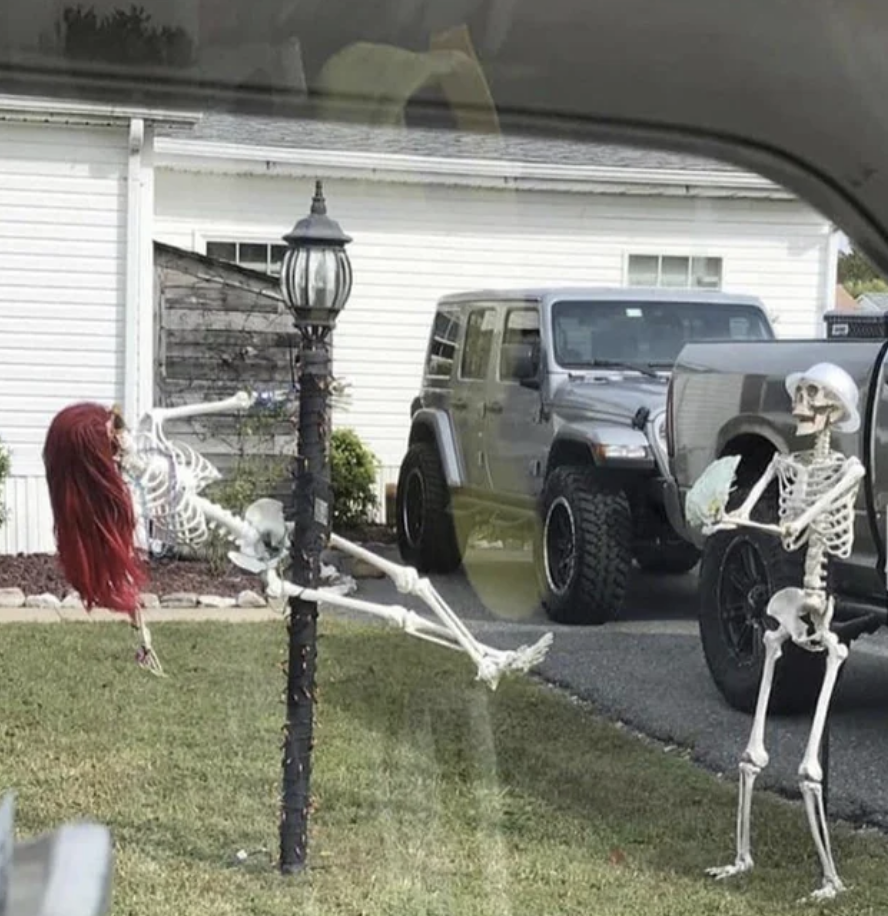skeleton with a wig on the pole and another skeleton with fake money