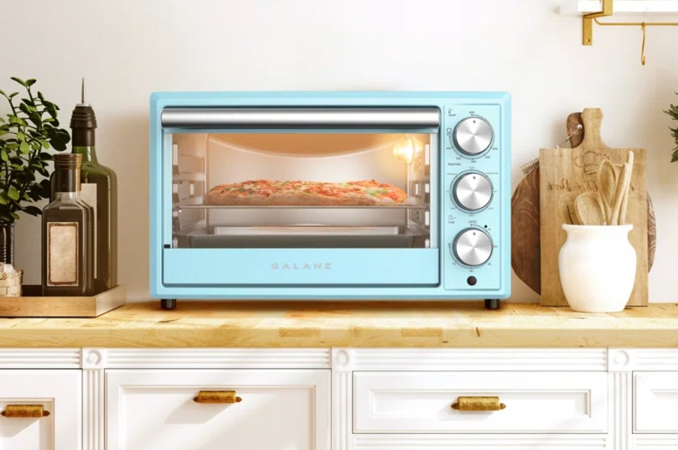 the light blue toaster oven with a pizza inside, on a decorated kitchen counter