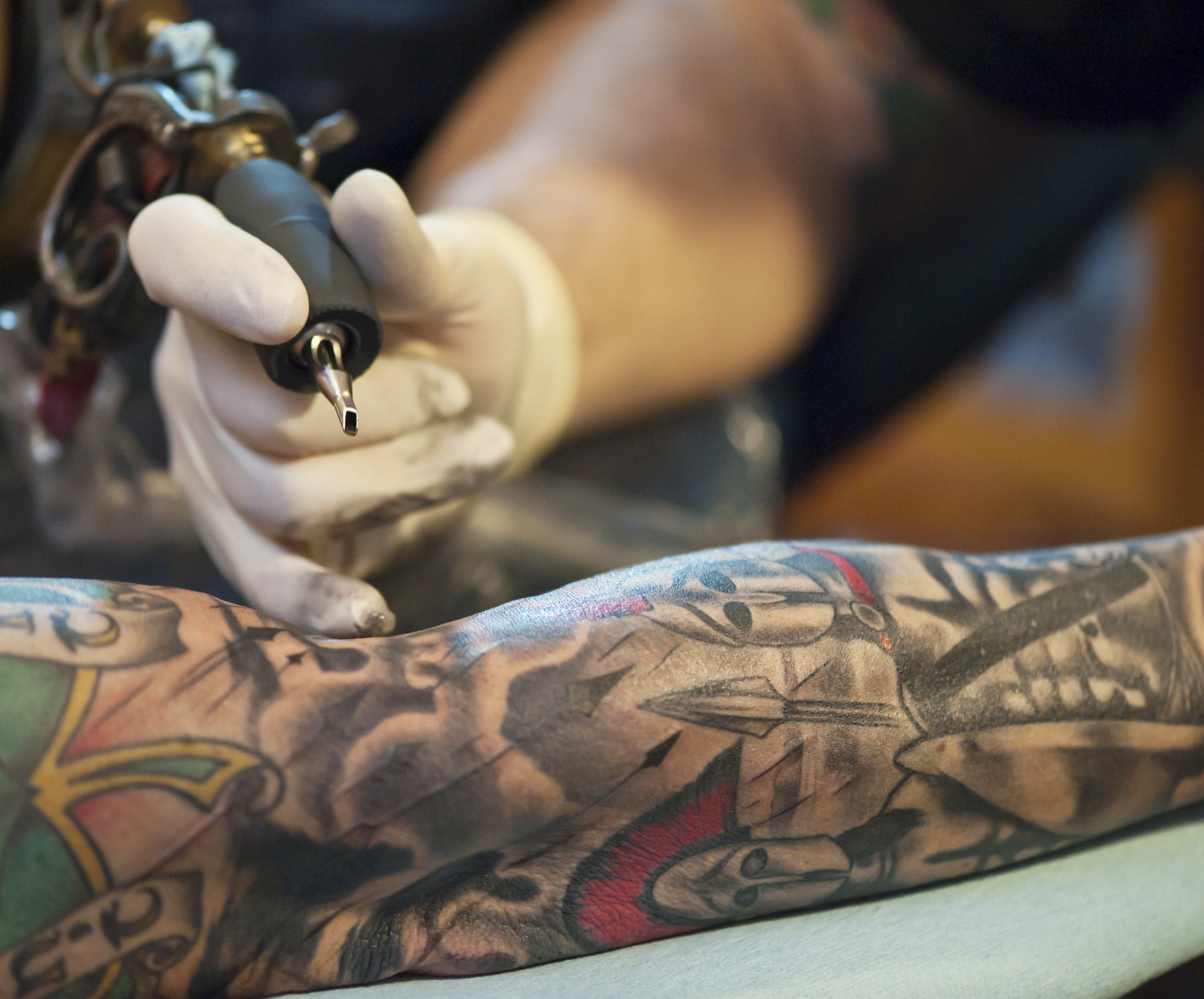 A tattoo artist working on someone&#x27;s arm