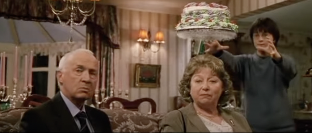 Harry Potter holding a hovering cake over a woman and a man