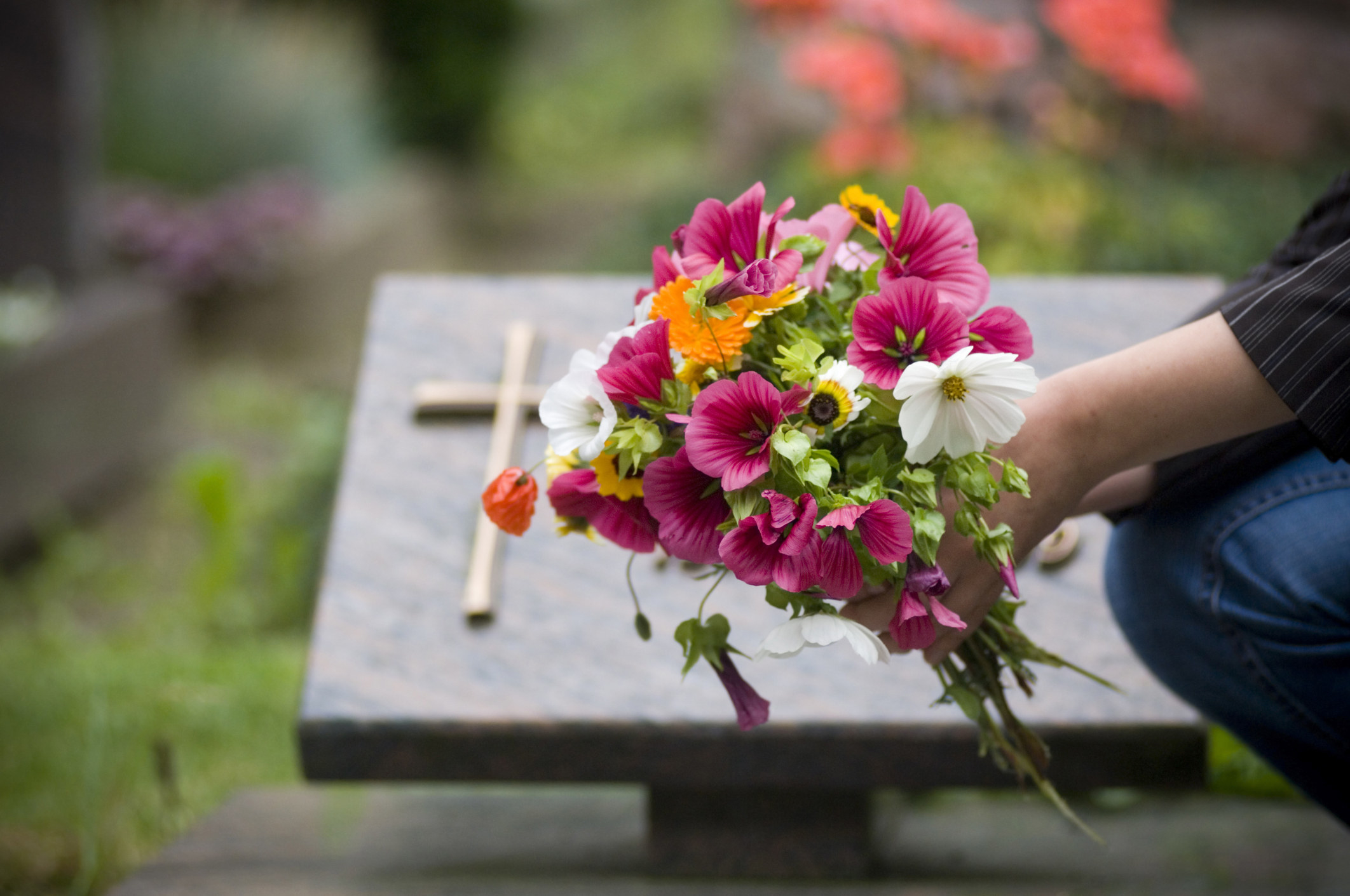 person leaving flowers at a grave