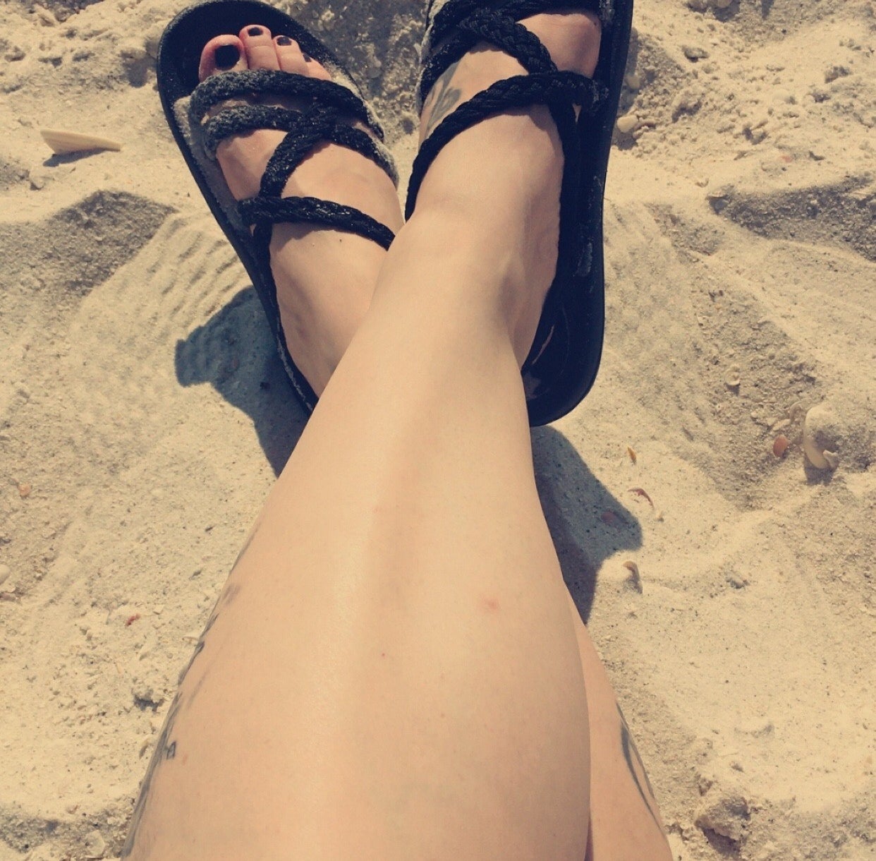 a reviewer wearing the black sandals at the beach