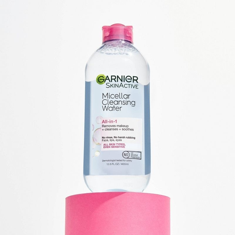 A bottle of micellar water on a pink stand