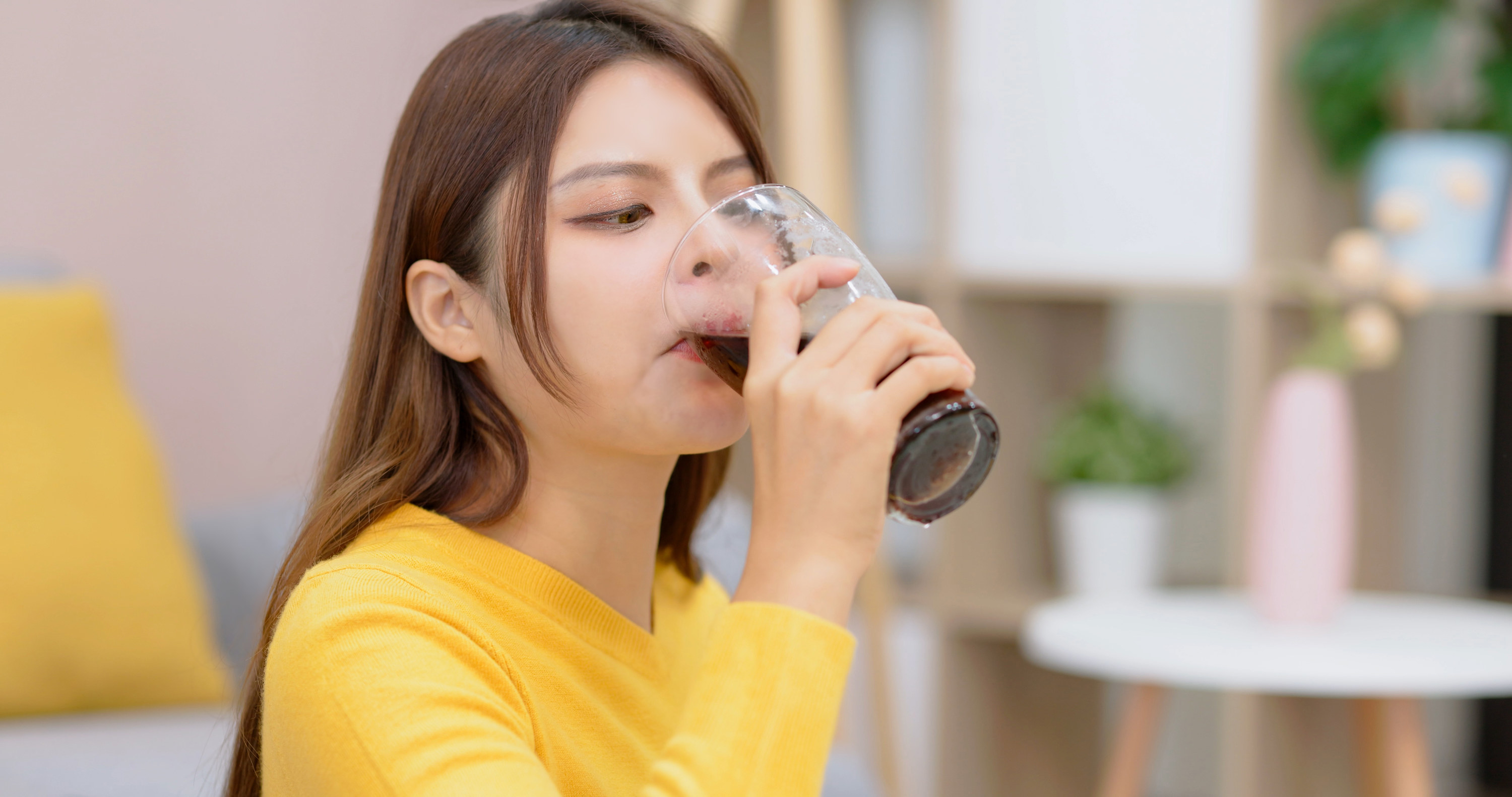 A young woman drinking soda from a glass