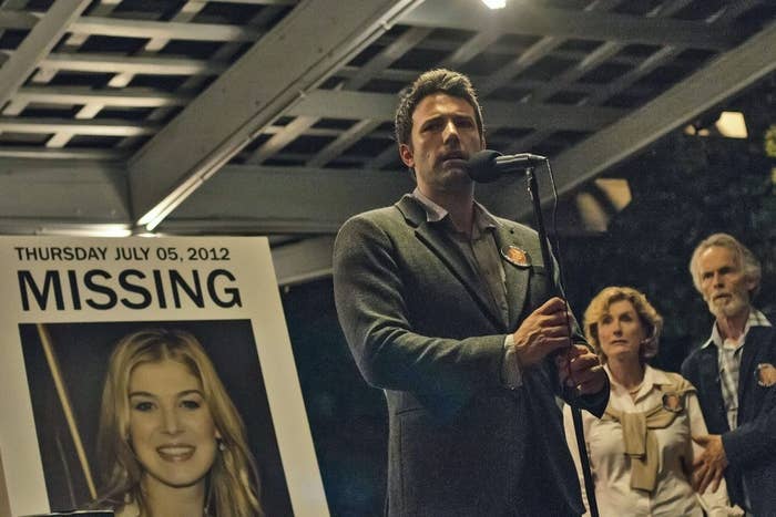 In a scene from the movie, Nick is standing in front of a microphone with a &quot;Missing&quot; poster of his wife