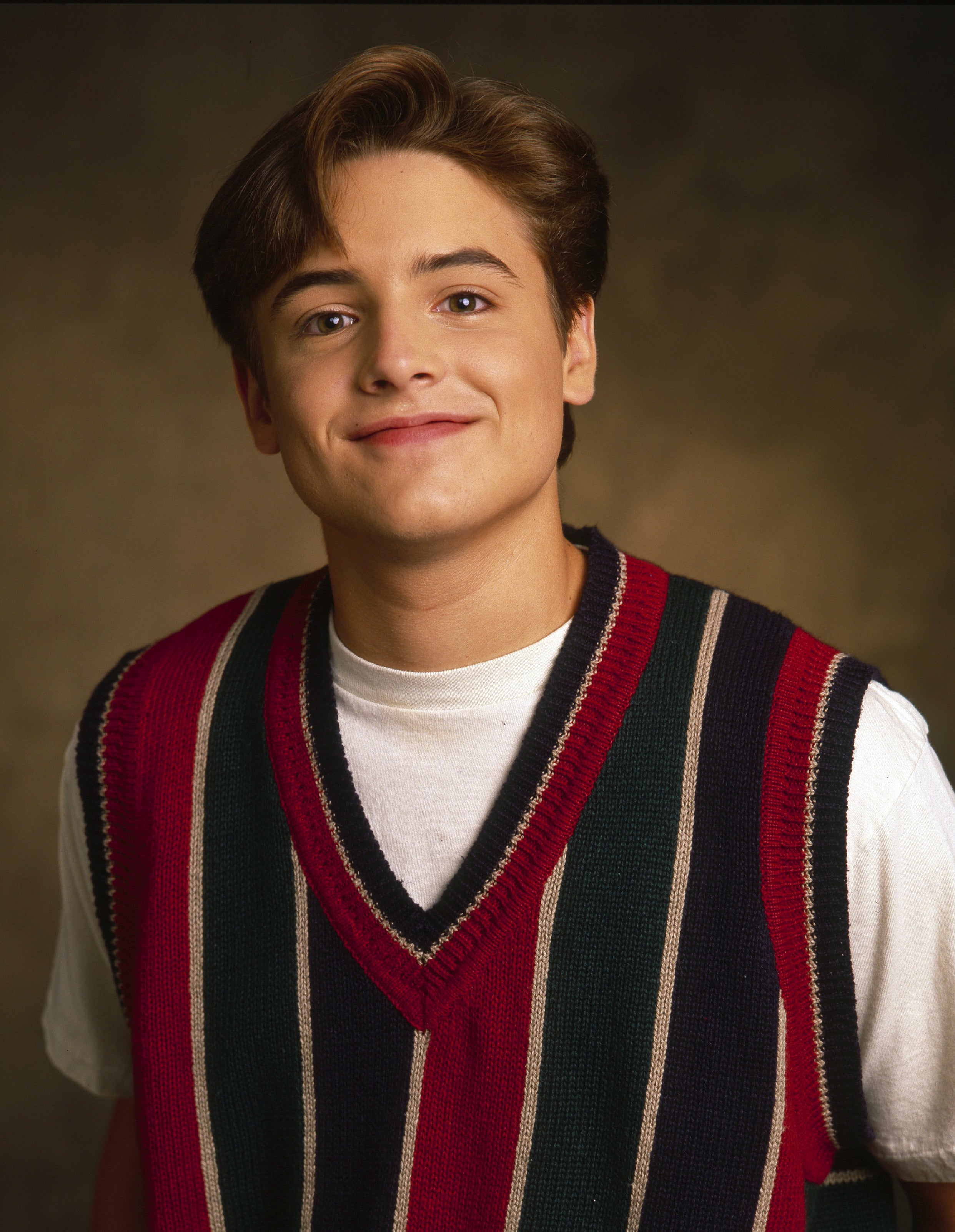 Close-up of Will as a young man smiling and wearing a striped vest