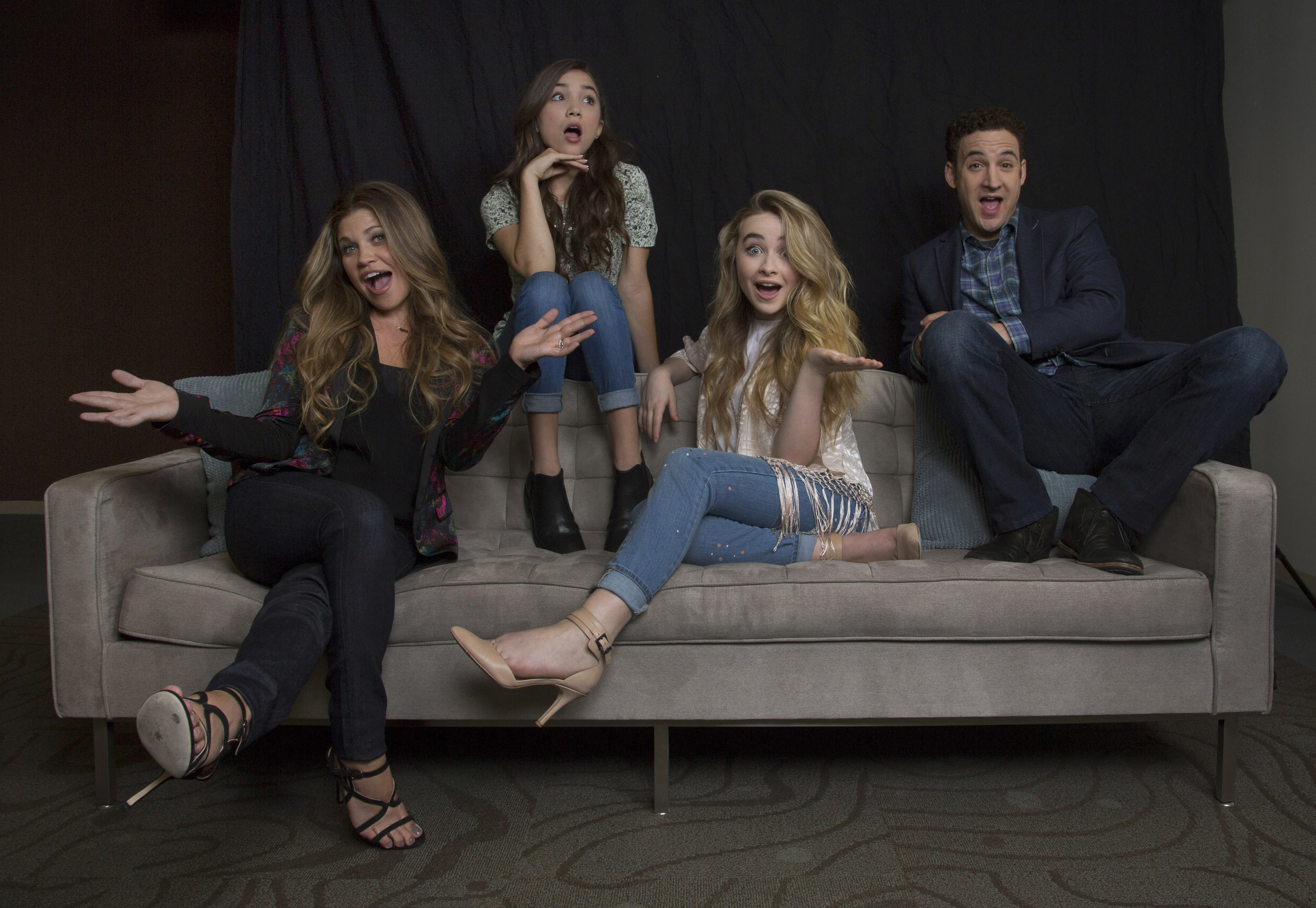 Cast members sitting together on a couch