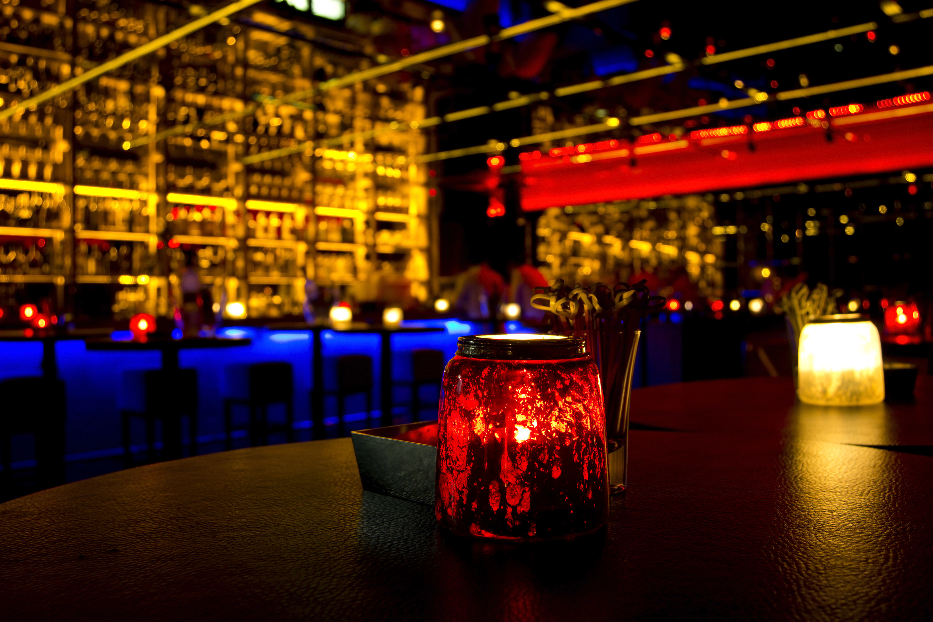 A dark restaurant setting with candles and a bar in the background