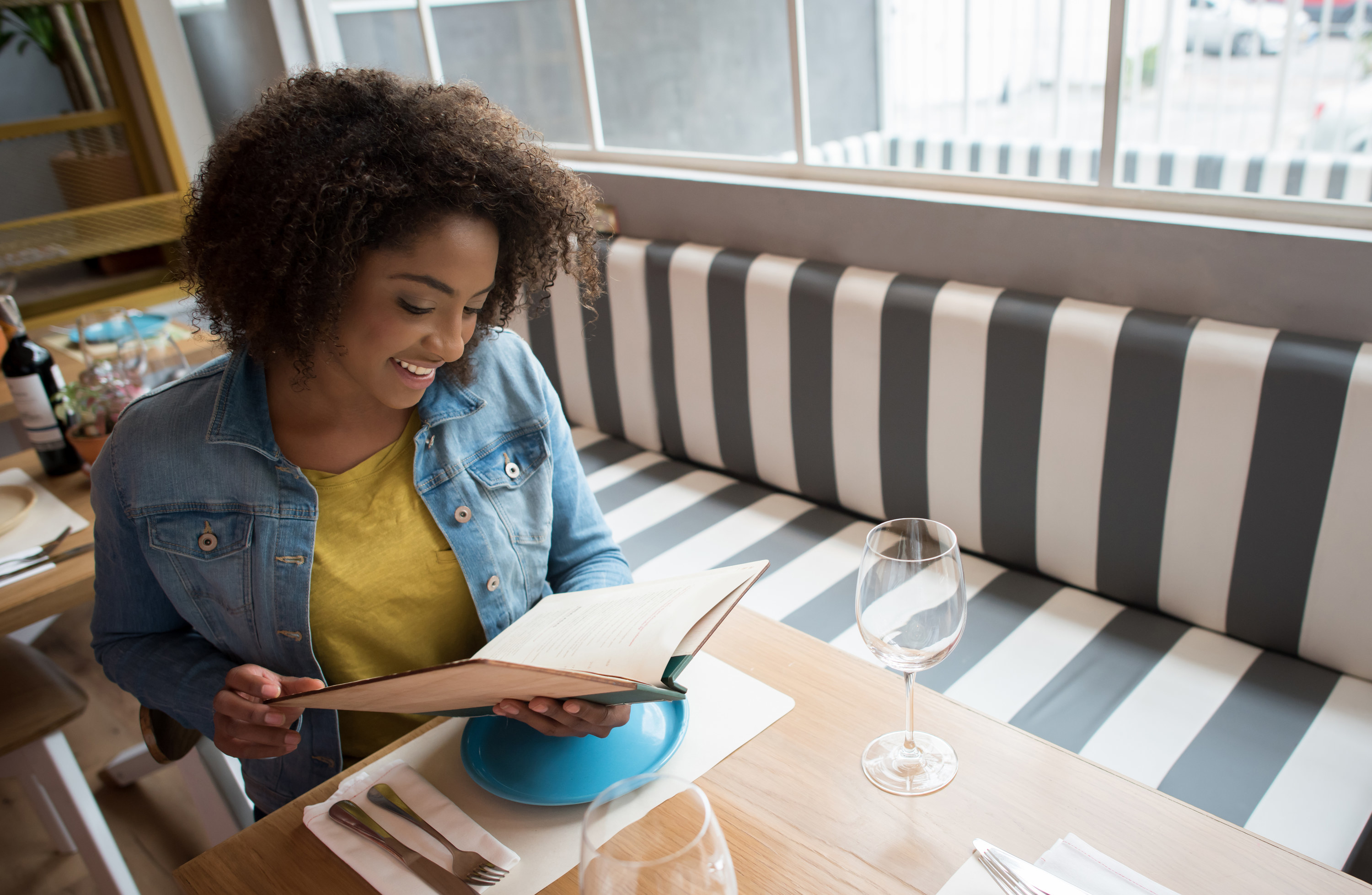 A woman in a jean jacket looking at a menu in a restaurant