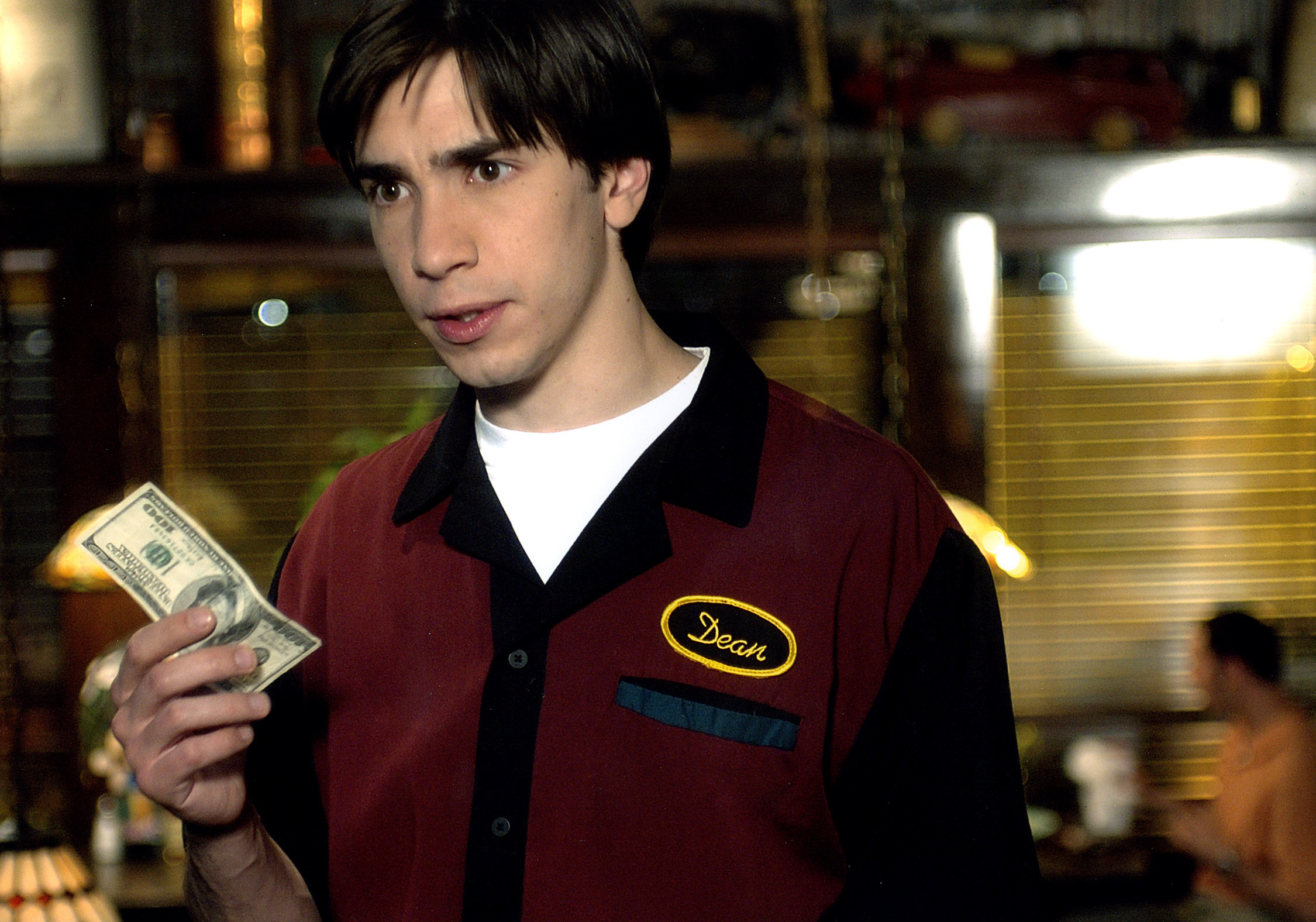Justin Long holding $100 in Waiting