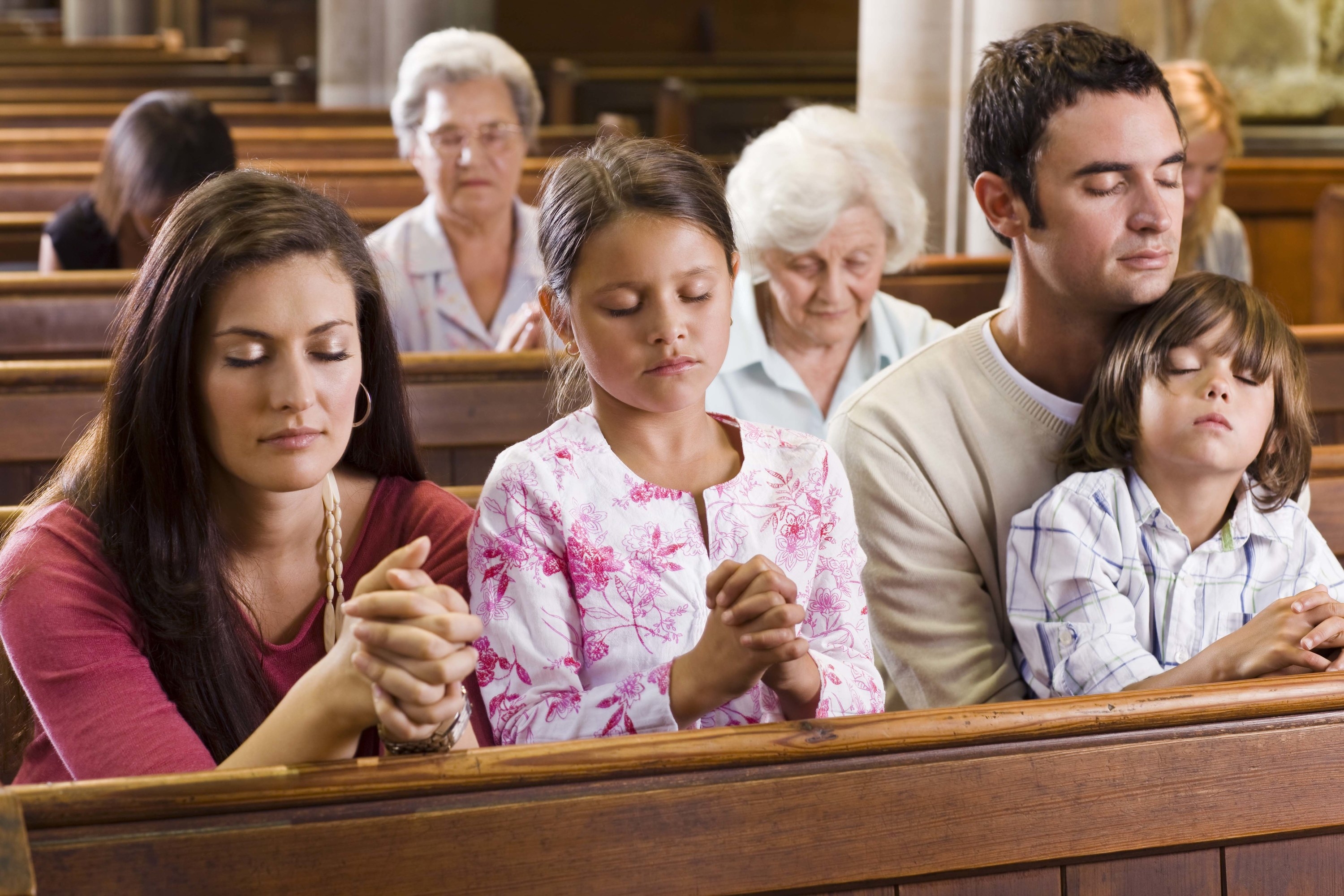 A family prays in a church pew