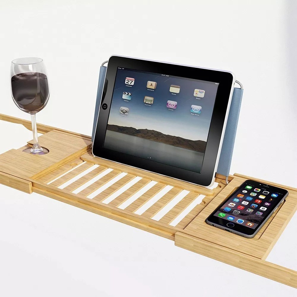 The bath caddy with an ipad and phone and glass of wine