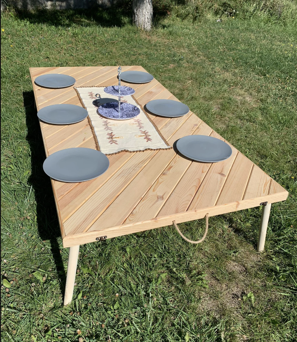 A low wooden picnic table is shown outside on grass