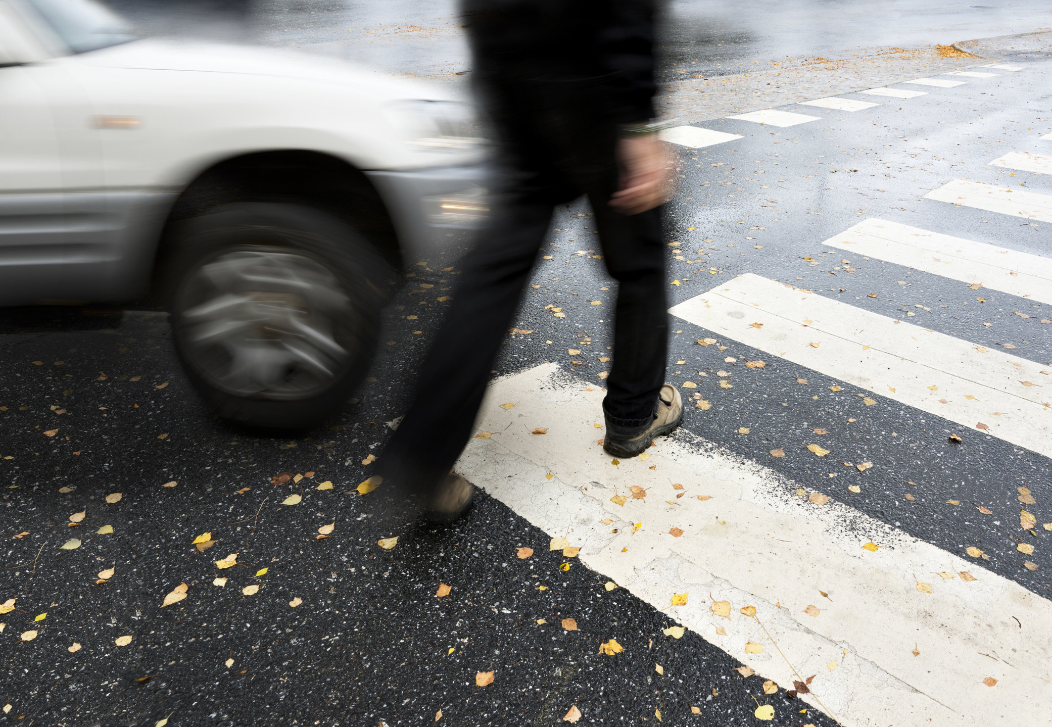 A person crossing a crosswalk about to be hit by a car