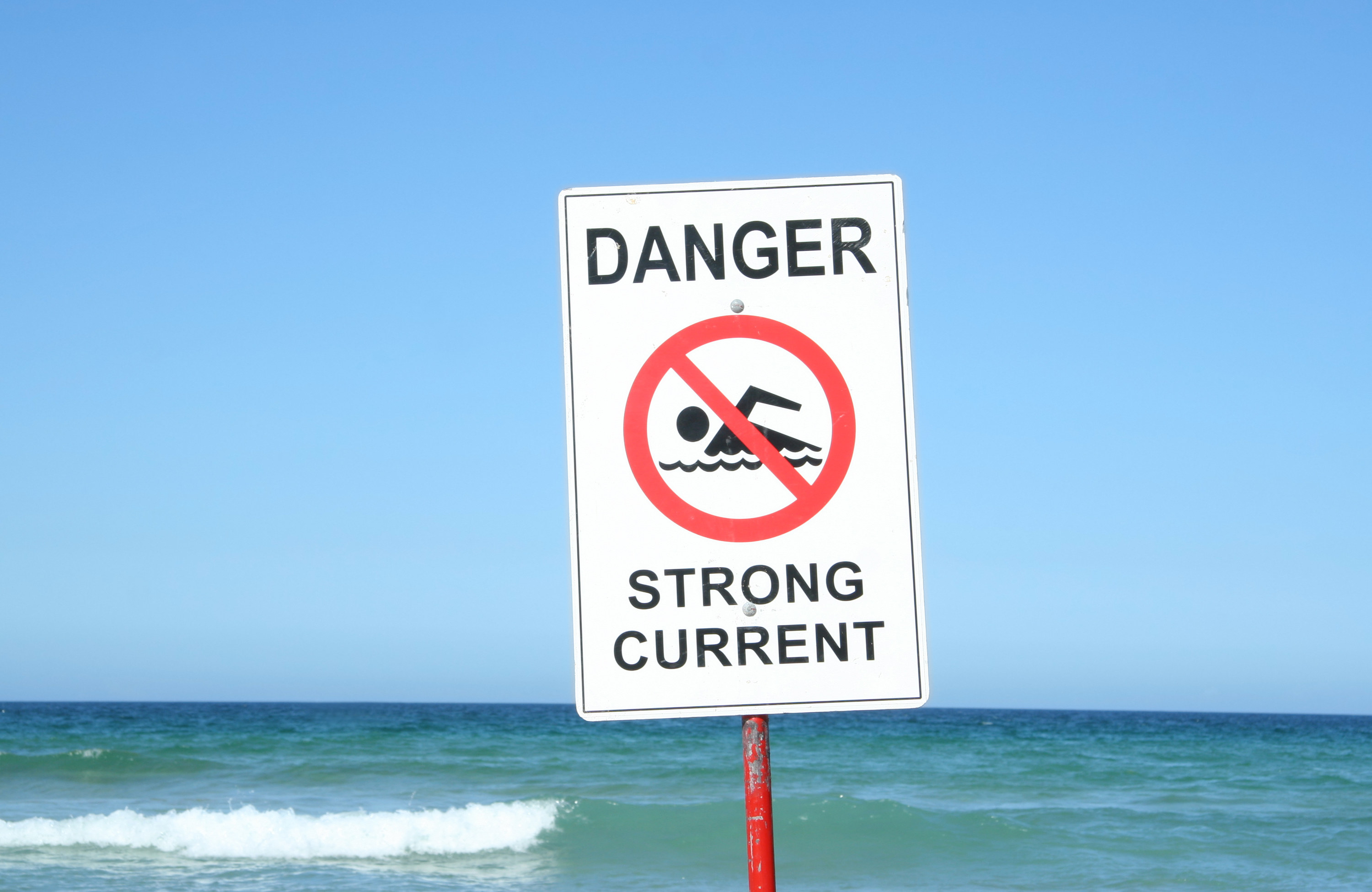 A &quot;Danger Strong Current&quot; sign at a beach