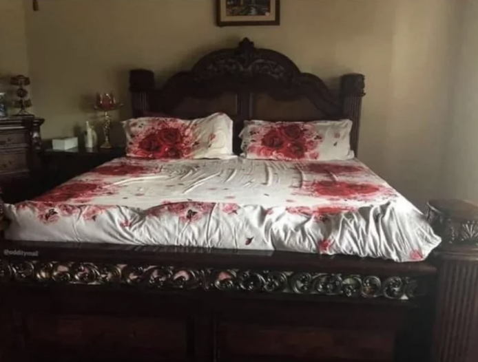 a set of white sheets with clusters of red roses that look like pools of blood