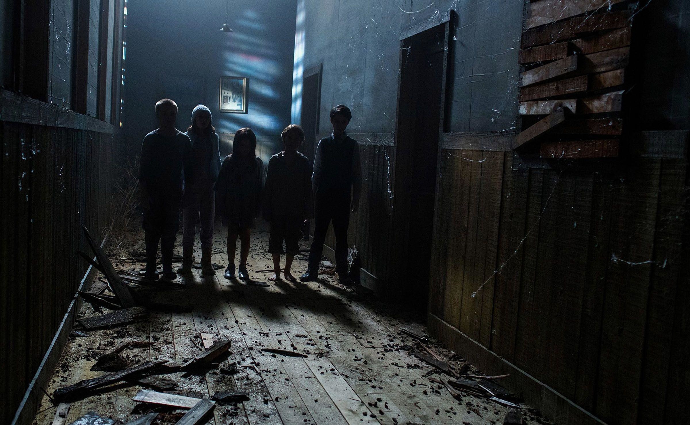 A group of creepy children stand in a decrepit hallway