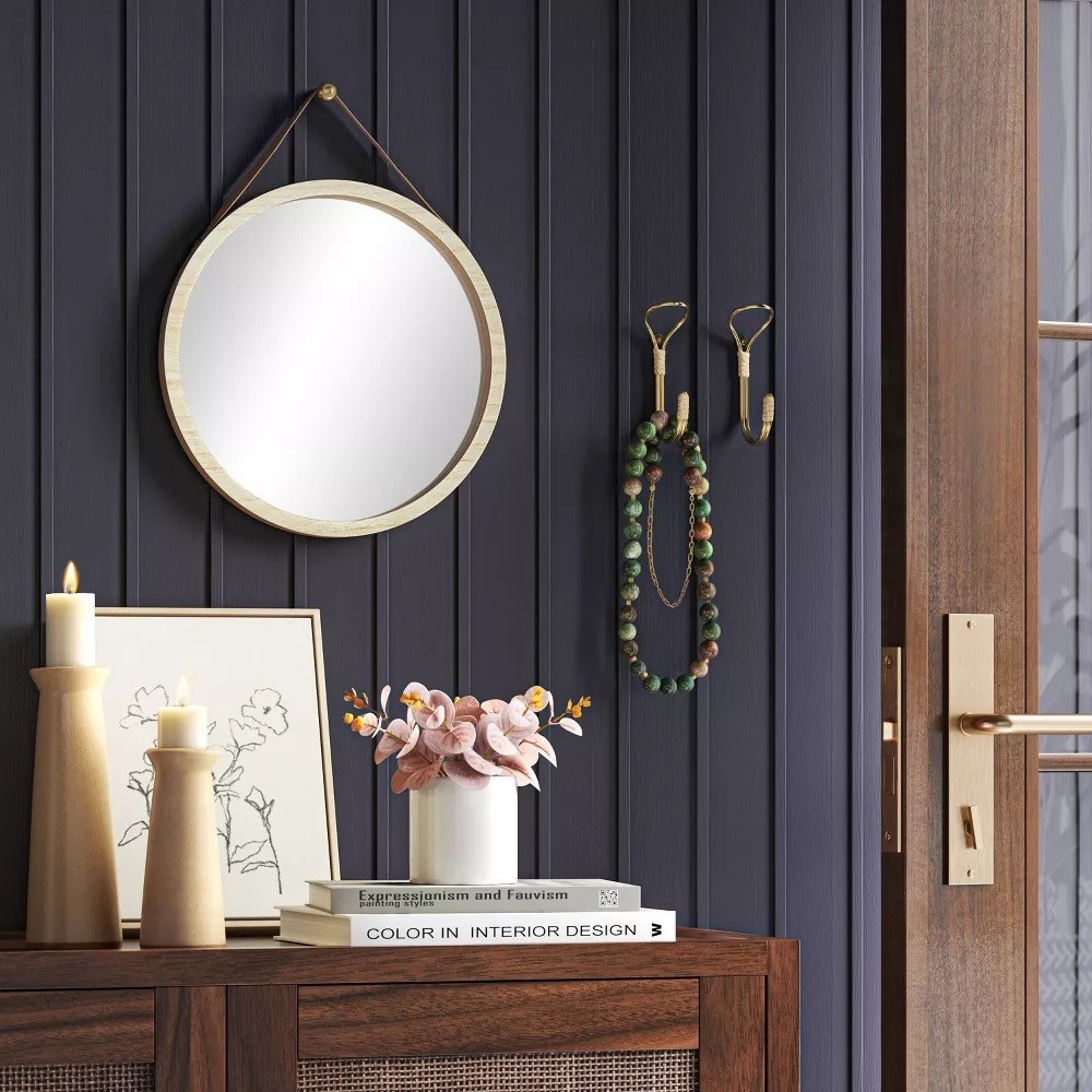 the round mirror hanging in an entryway