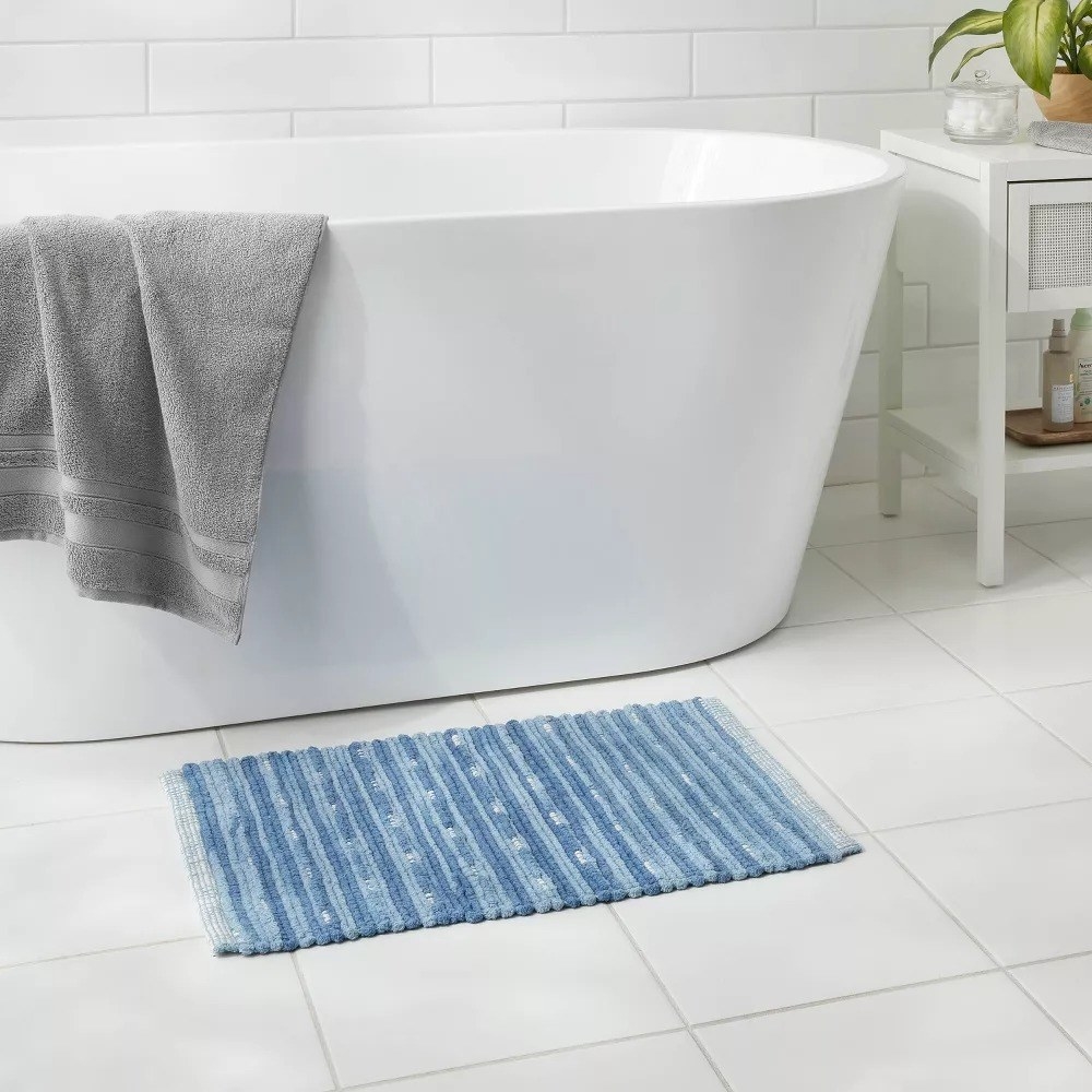 the blue bath rug with a dot and stripe pattern underneath a bathtub