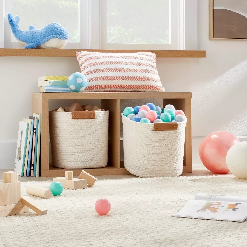 two of the coiled storage baskets holding various toys in a playroom