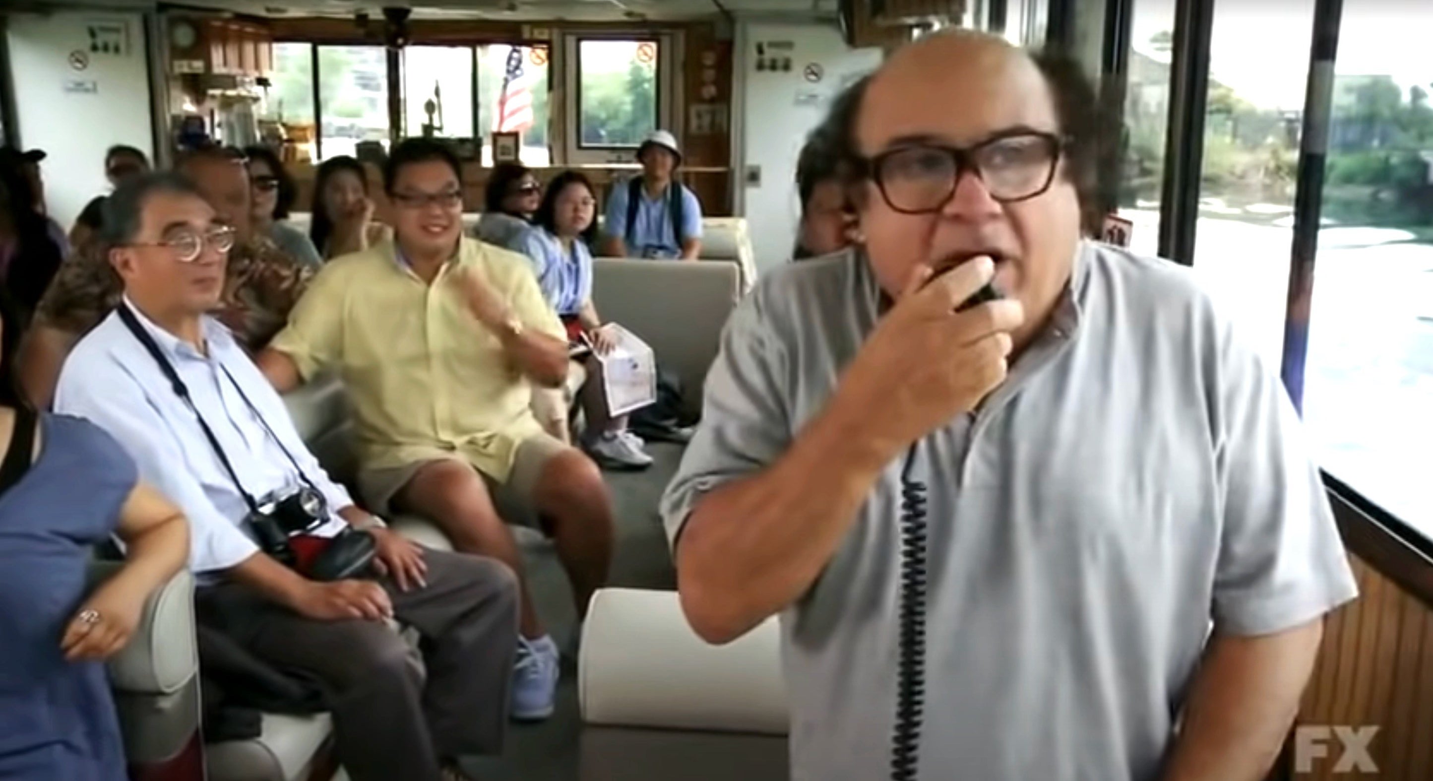 Danny DeVito giving people a tour and speaking on an intercom