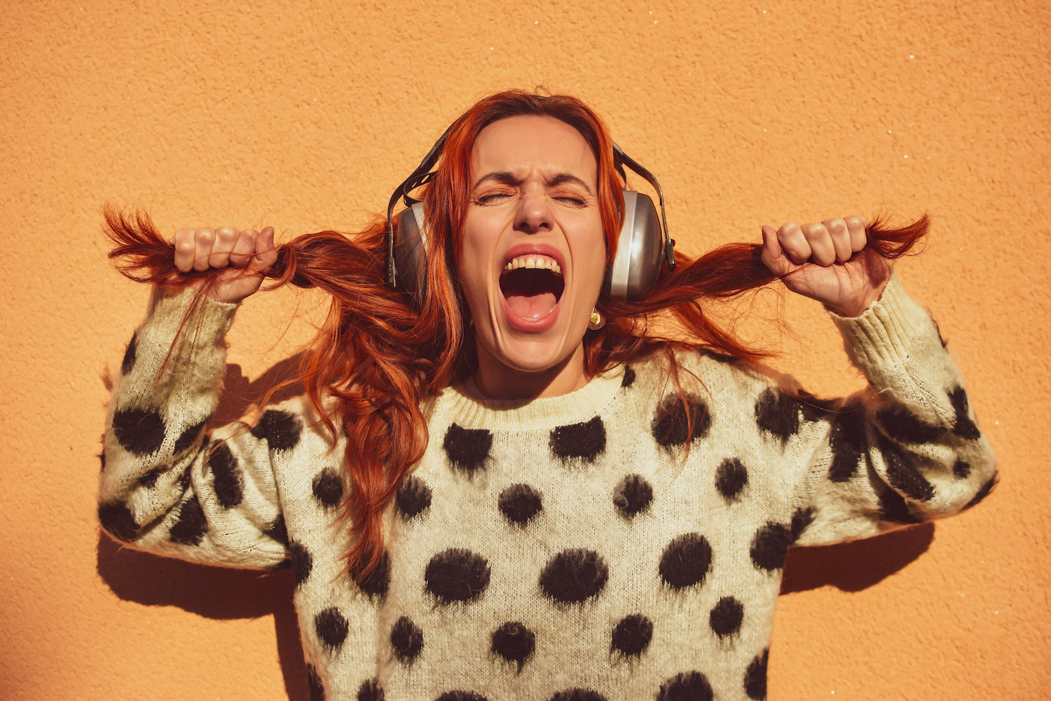 A woman pulling her hair and yelling while listening to music on her headphones