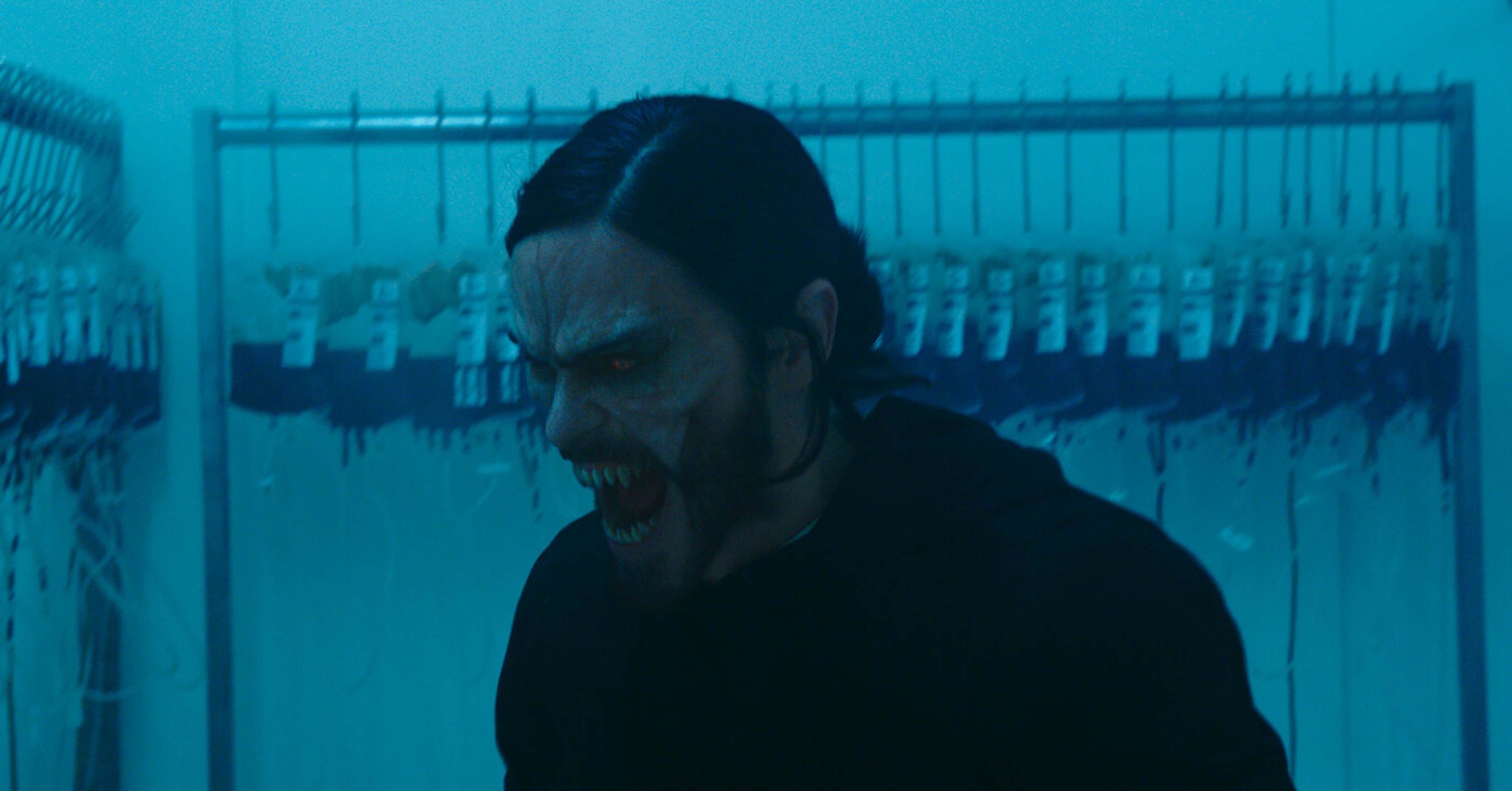 Morbius makes a scary vampire face in a room full of blood bags