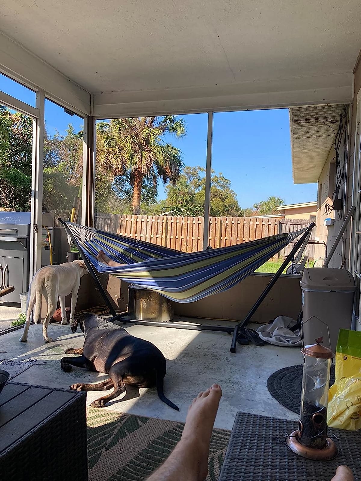 hammock set up on covered patio area with someone&#x27;s feet sticking out as they lounge