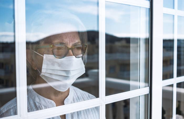woman wearing a mask standing at a window