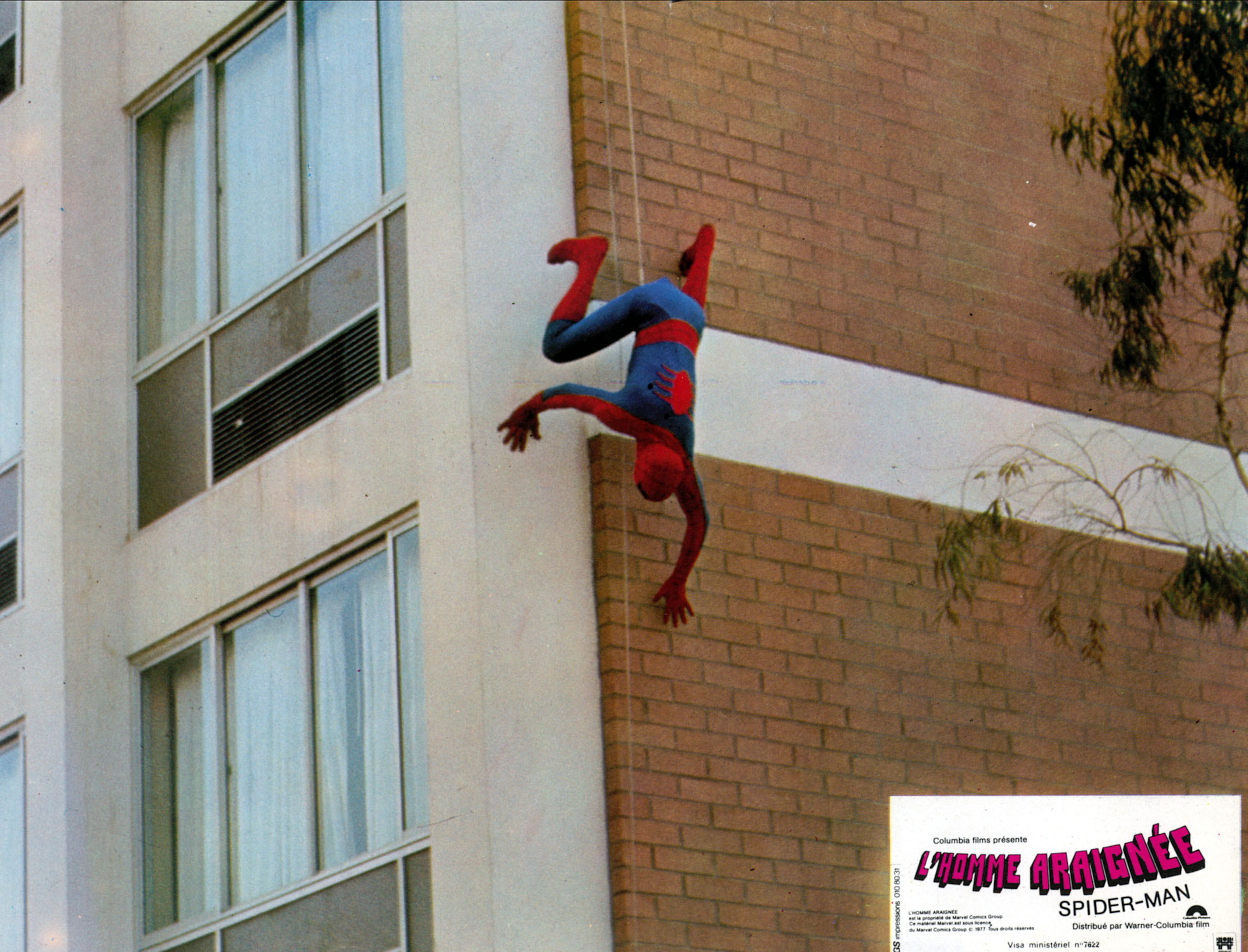 Spider-Man crawls down the wall of a building