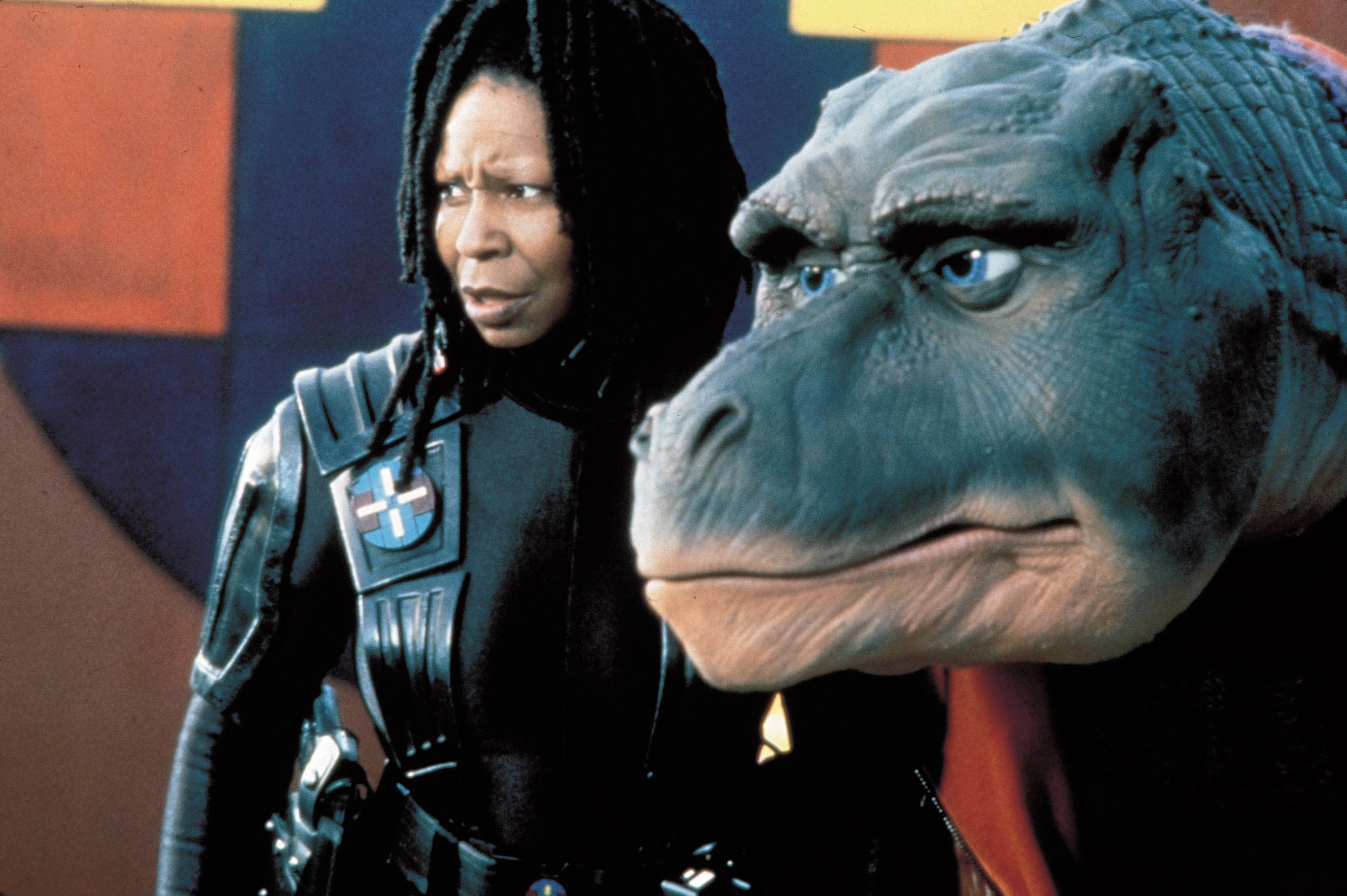 Whoopi Goldberg and a T-Rex stare off-screen with concern