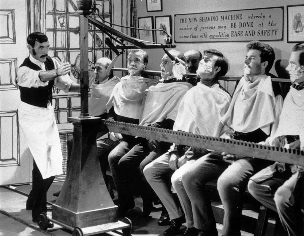men seated in a row to get shaved