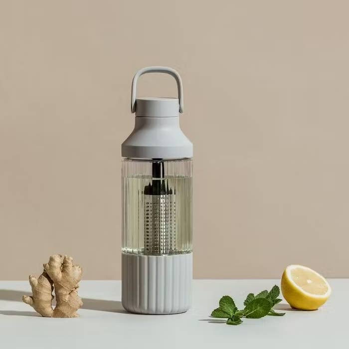 the bottle in pebble grey with infused water in it next to fresh ingredients