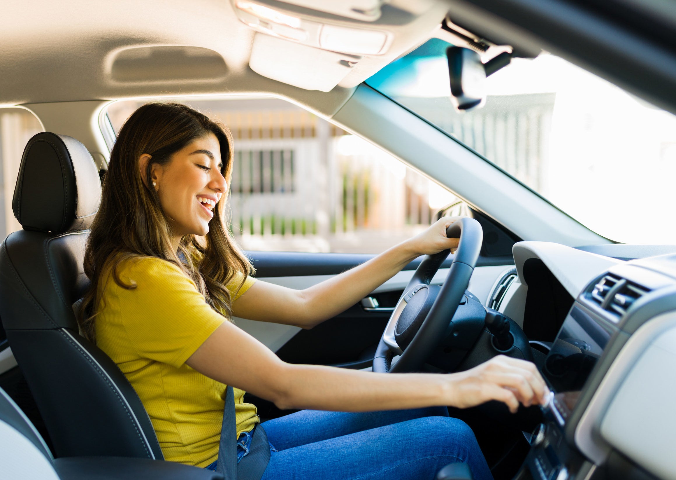 A woman raises the volume of a song on the radio while driving her car