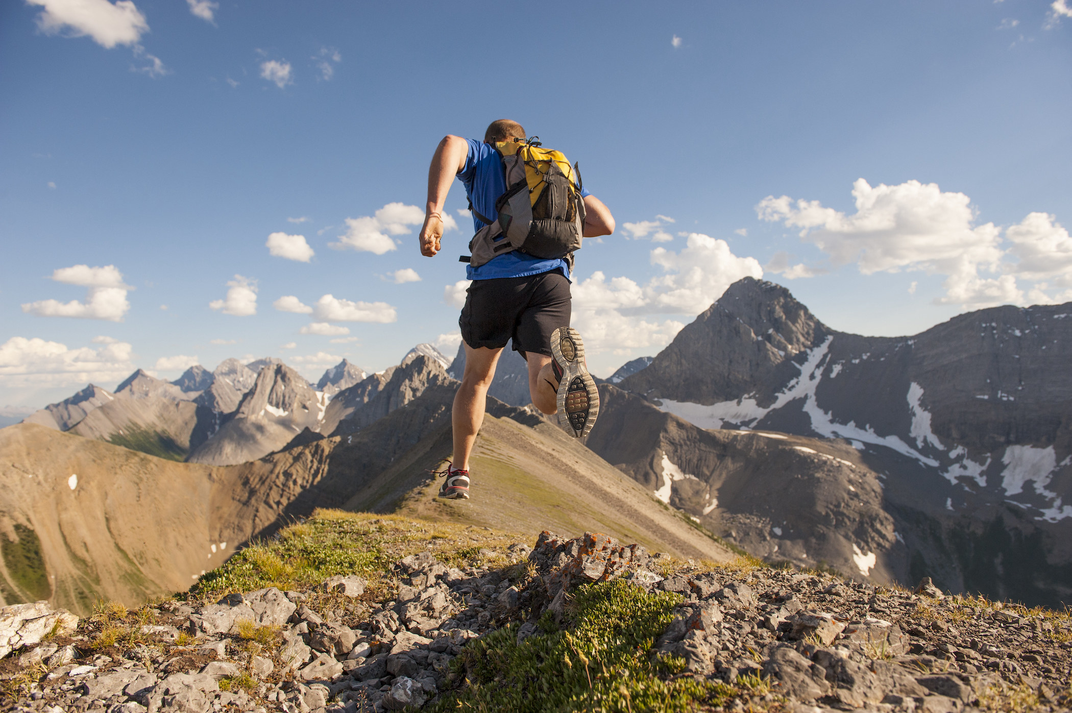 A man running through the mountains with a backpack on