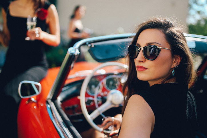 A woman posing for the camera in a nice convertible car